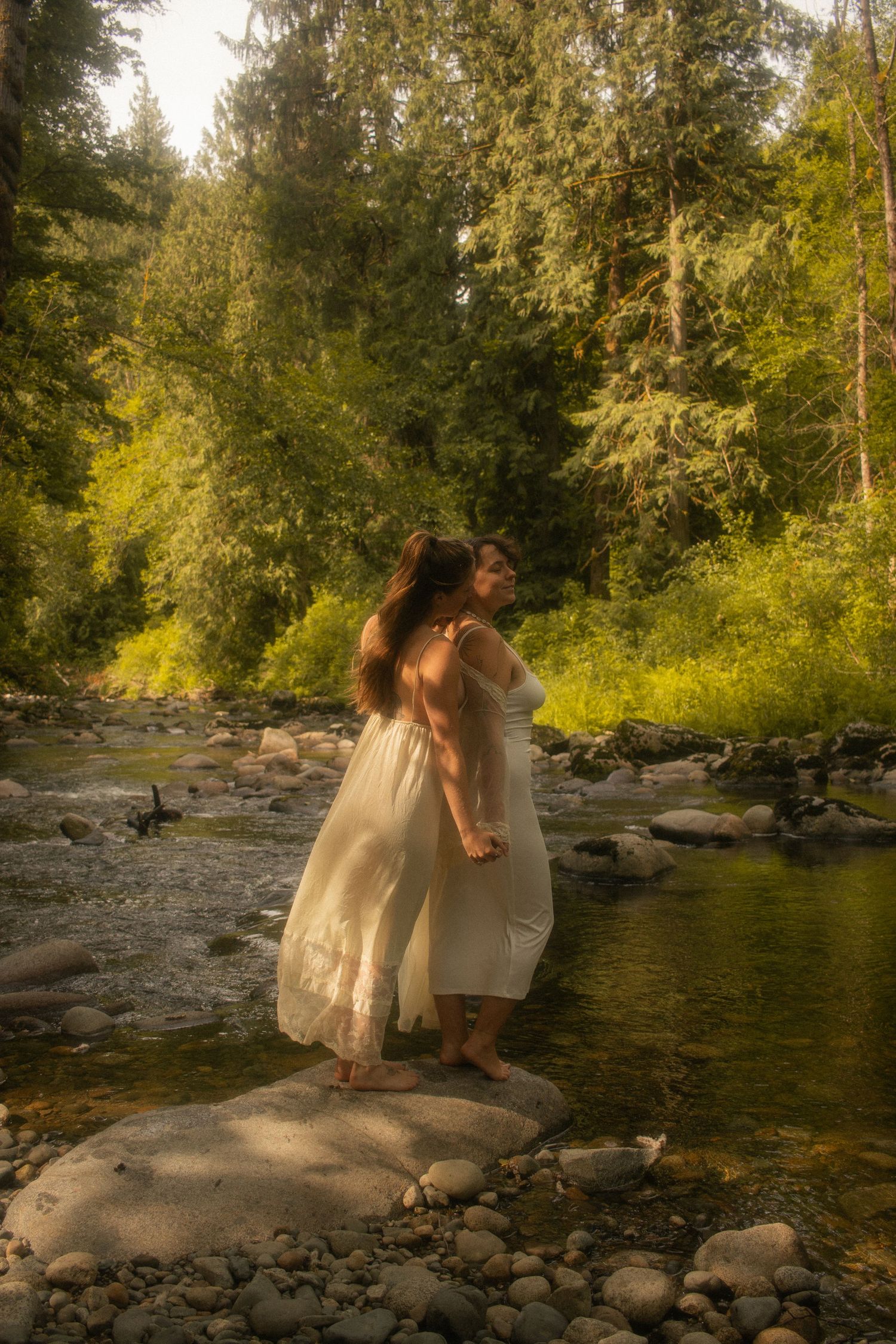 women standing together on a rock, hair and dresses blowing in the breeze.