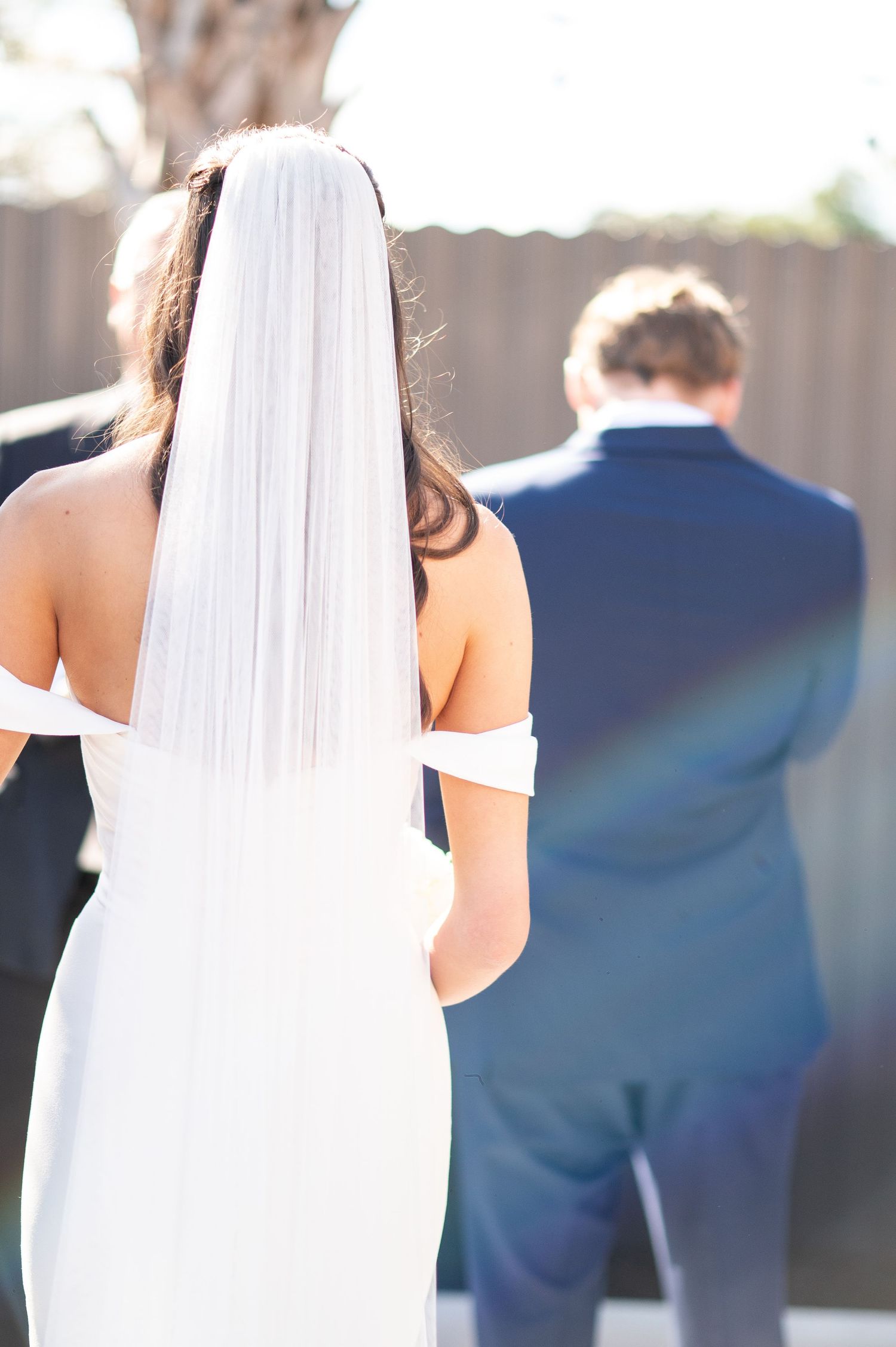 Wedding ceremony shots showing bride in white dress from behind with guests in background.