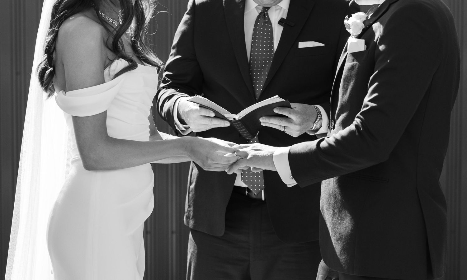 Black and white ceremony photos showing hands exchanging rings during a wedding.