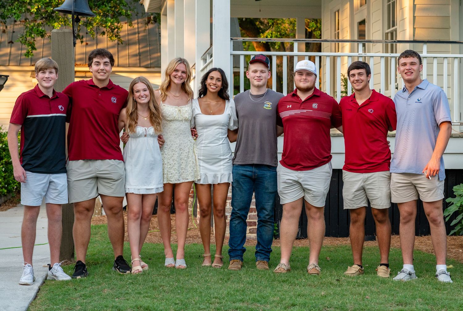 A group photo of students wearing red and khaki uniforms standing together outdoors on a sunny day.