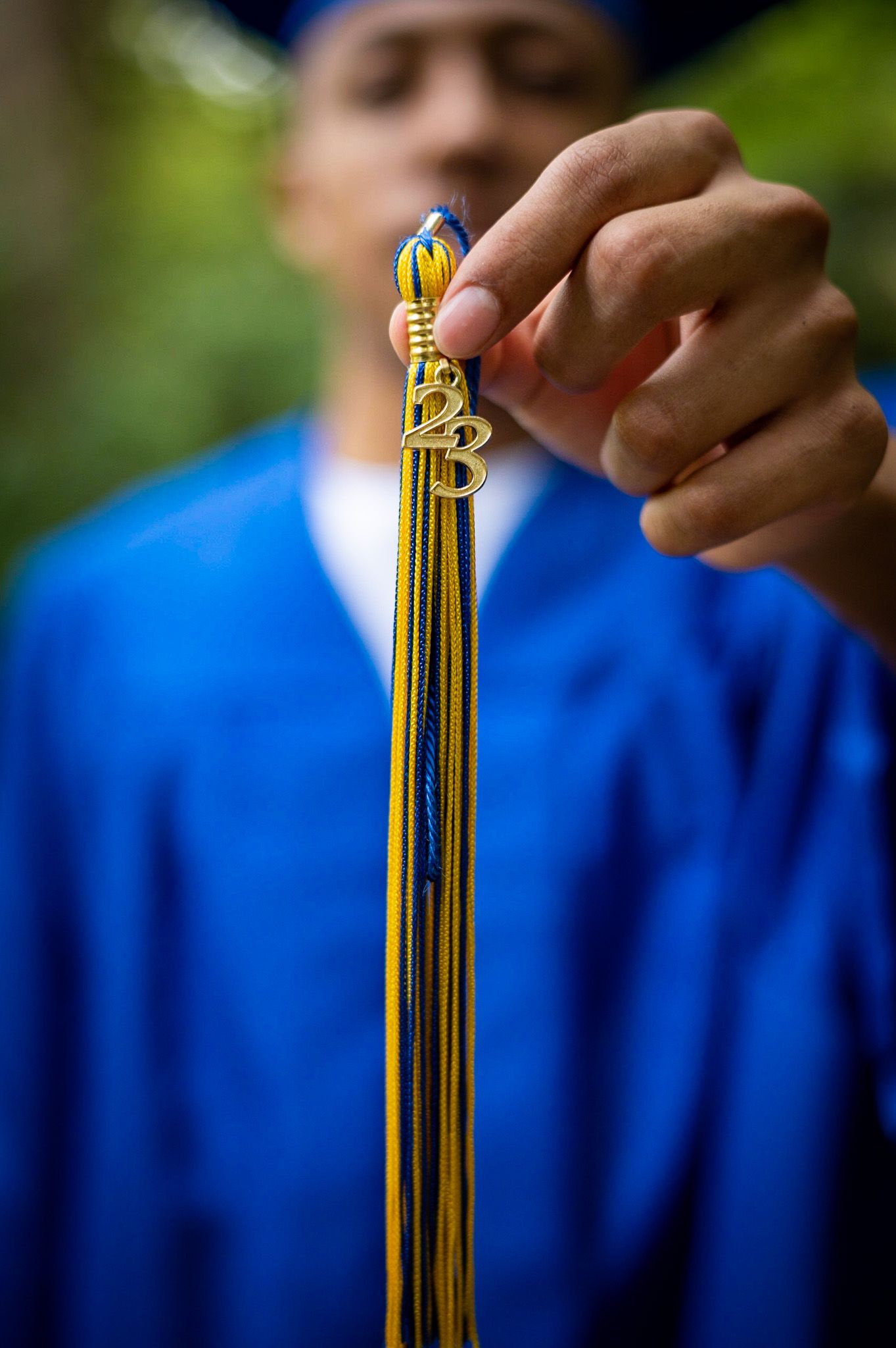 A close-up sequence showing hands adjusting yellow and blue graduation honor cords against a bright blue background.