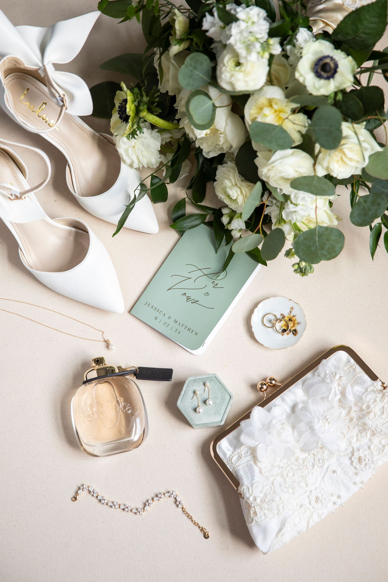 Wedding accessories flatlay with white shoes, flowers, perfume and mint green details.