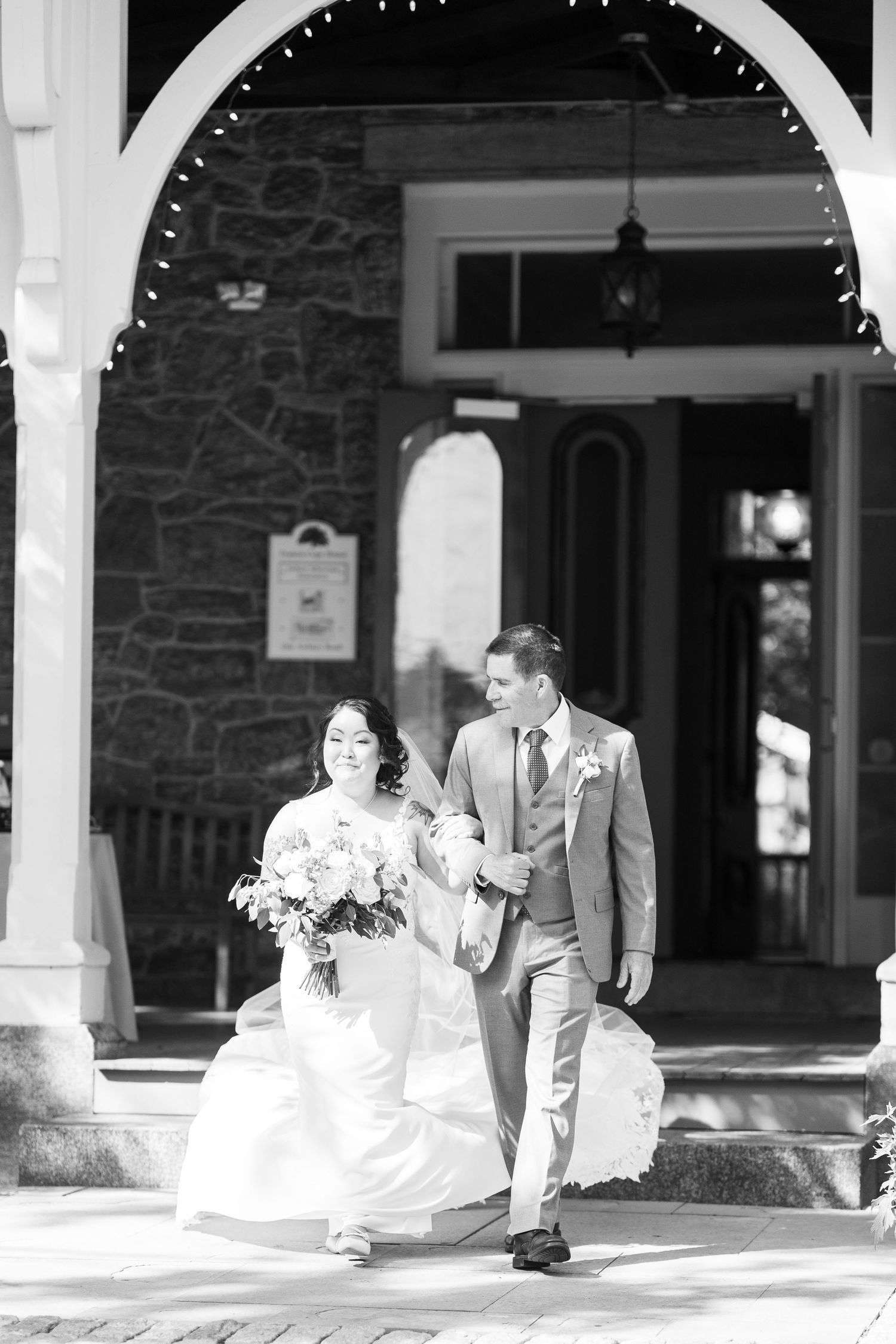 Wedding party members arranged in a line under a covered stone porch with white columns.