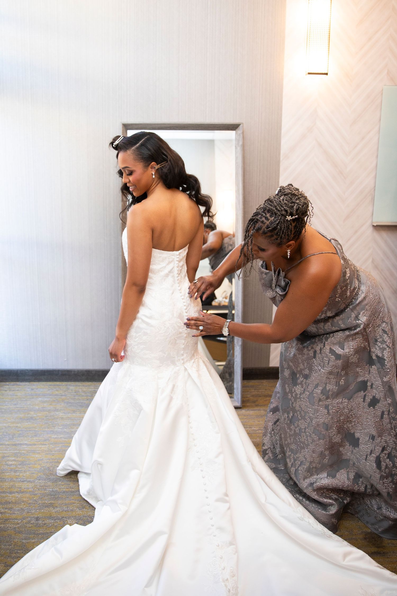 Final adjustments being made to a white wedding gown's back closure.