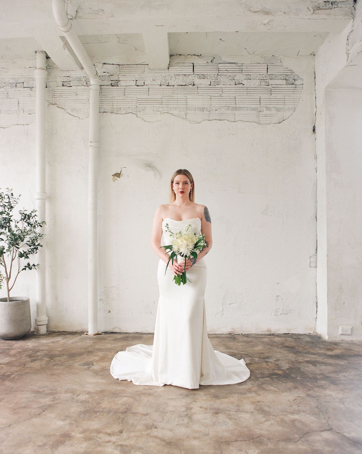 Minimalist bridal photoshoot in spacious white industrial room with concrete floors.