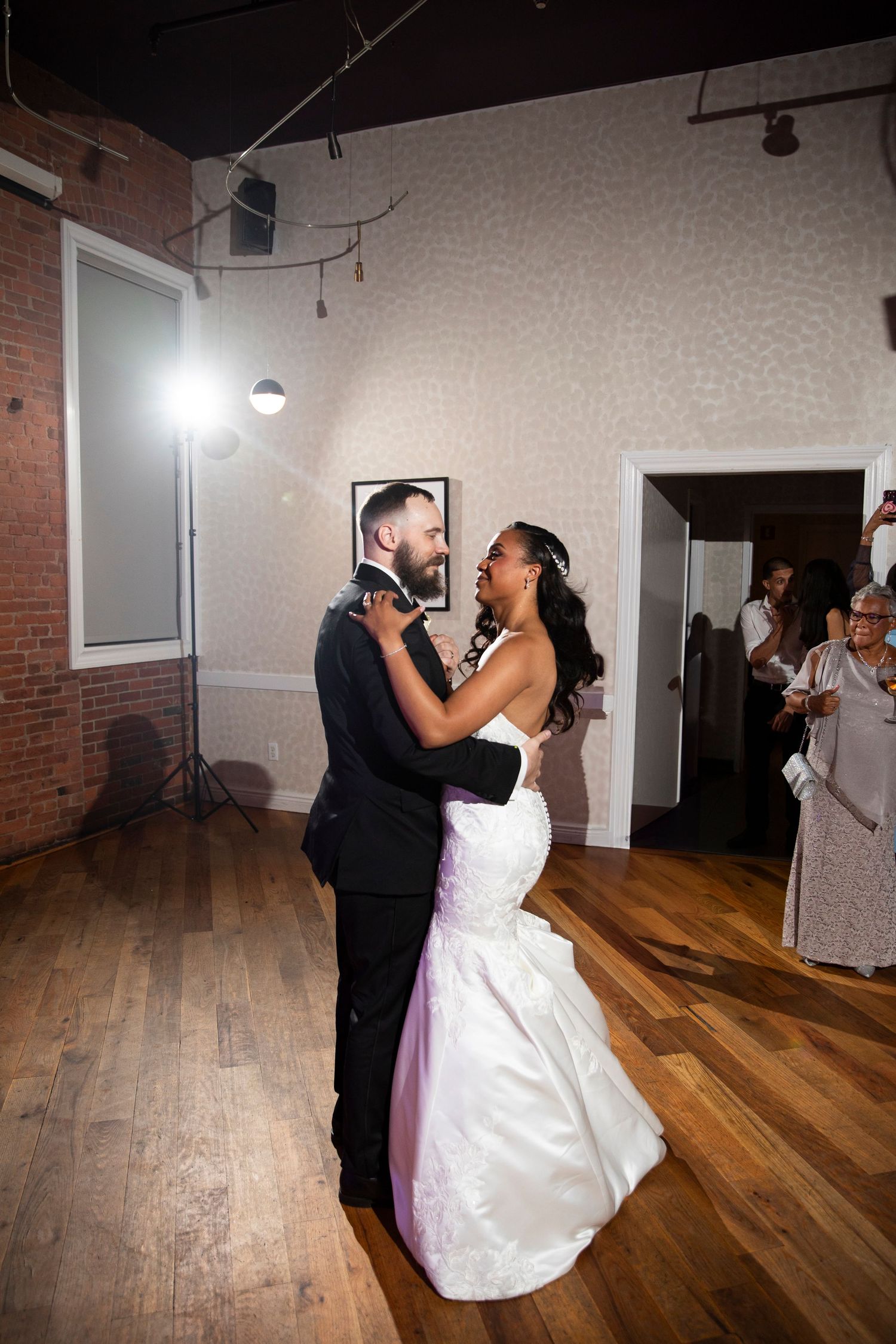Couple sharing a romantic dance in a studio space with hardwood floors and brick walls.