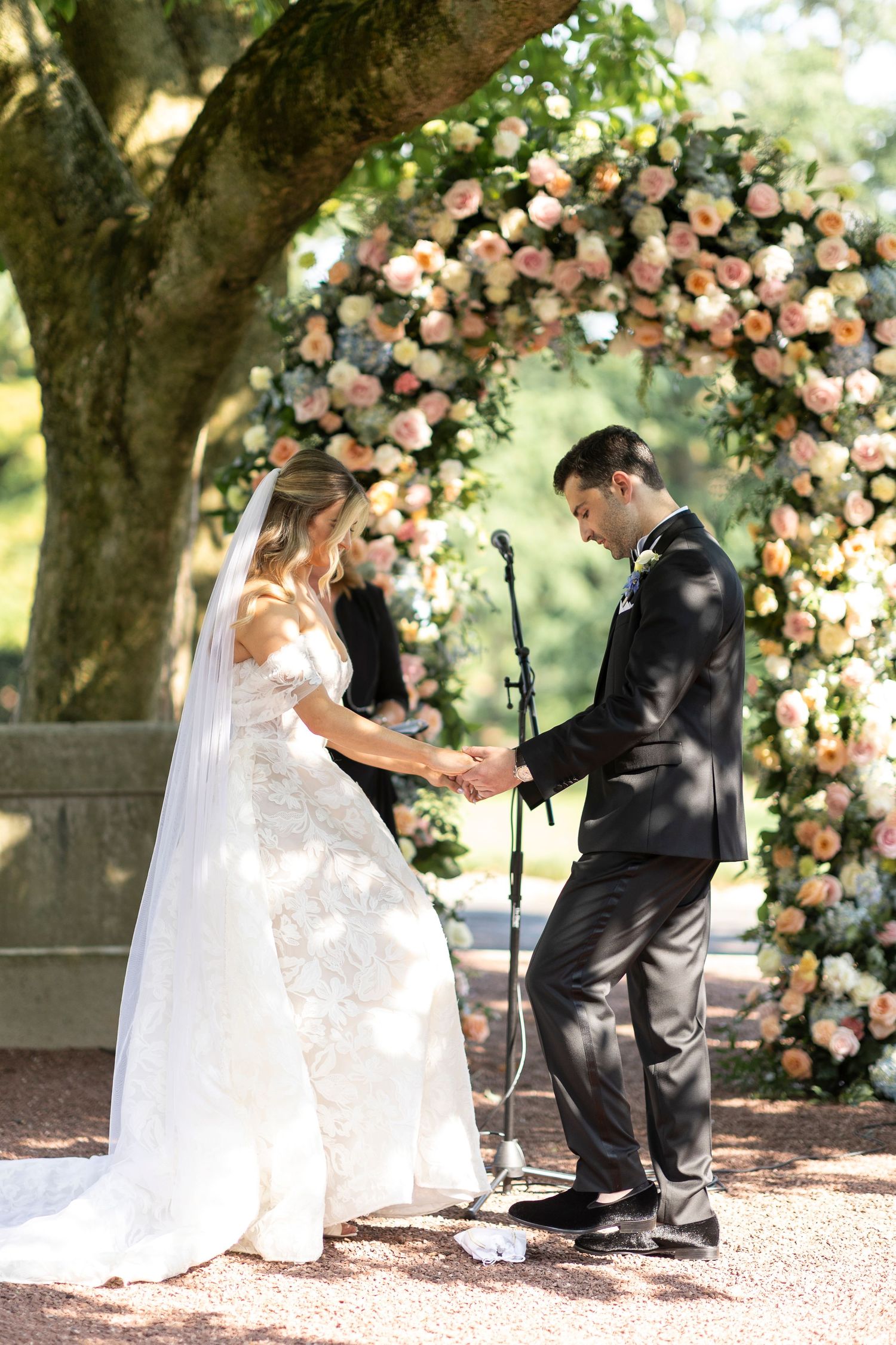 Wedding ceremony moment captured under a beautiful floral arch with pink and white roses.