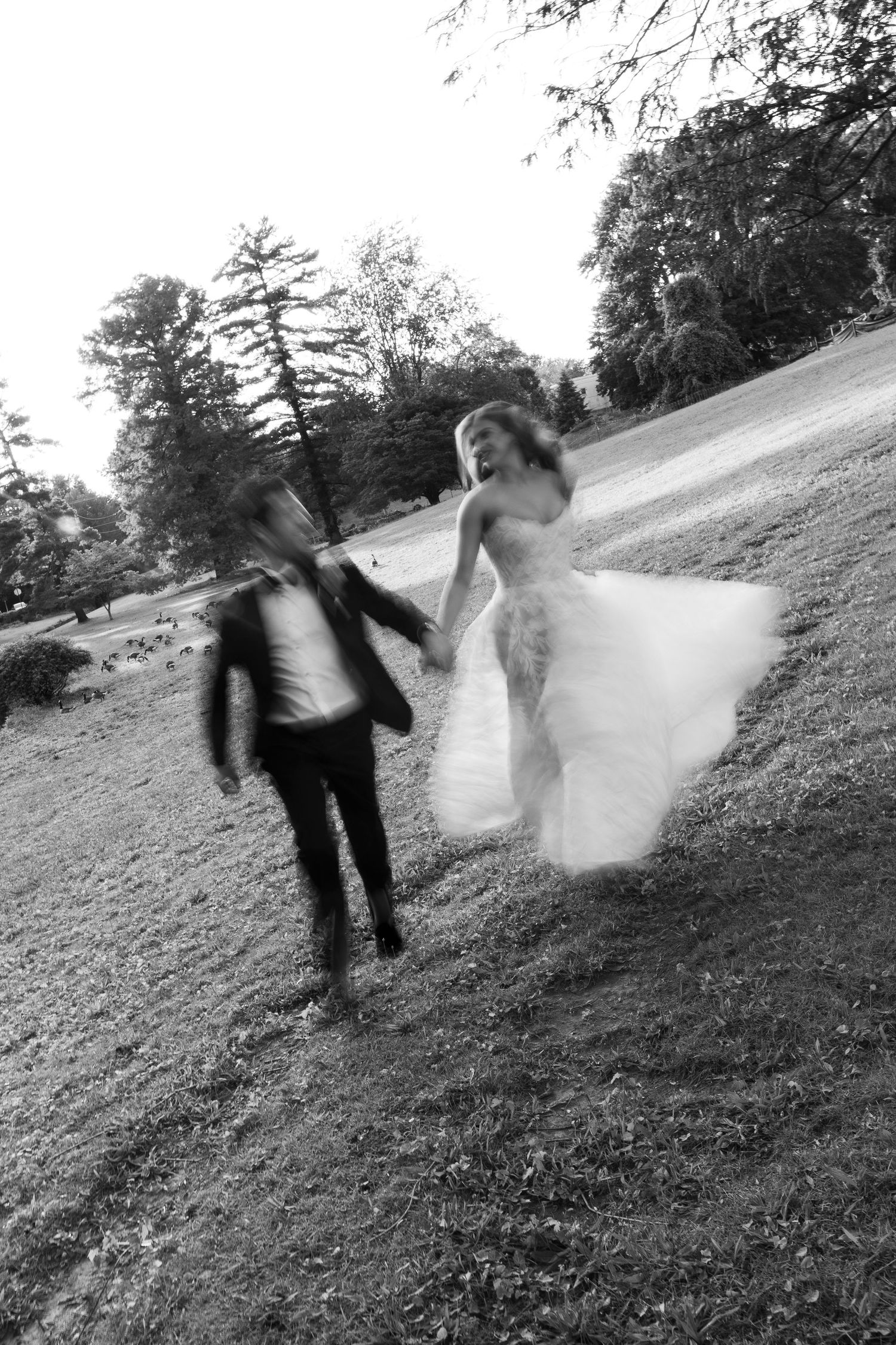 Motion-blur photos of couple running playfully on a grassy hillside.