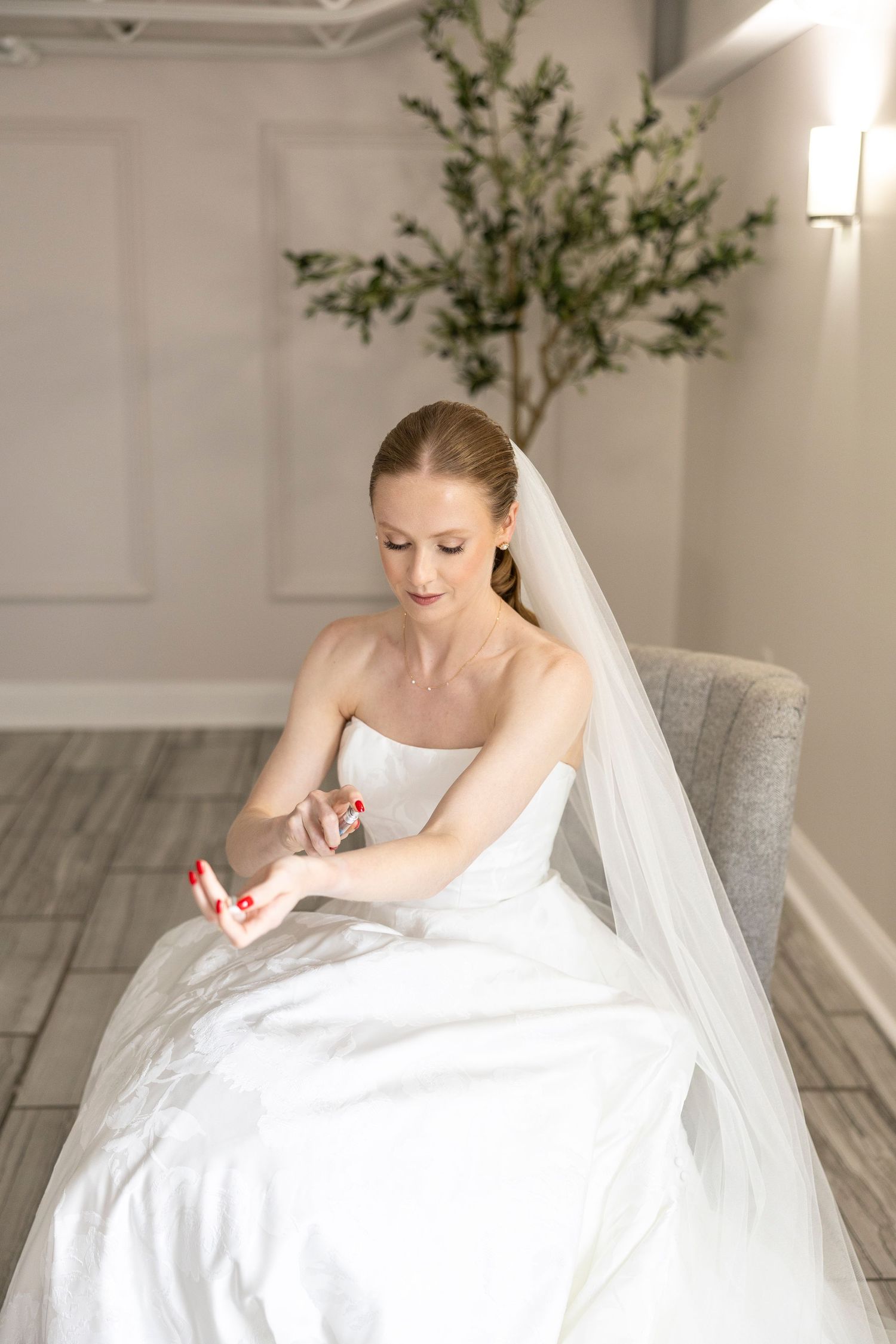 Bride seated in modern setting with decorative tree preparing final details.
