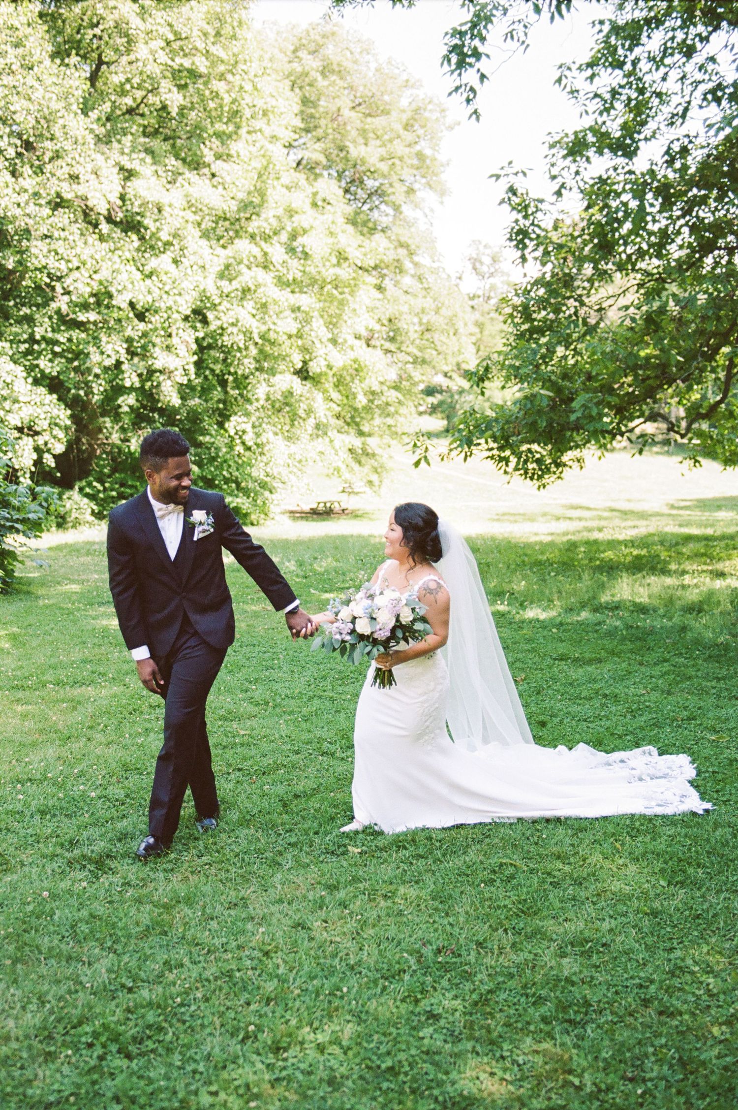 A wedding couple poses playfully on a lush green lawn during their photo session.