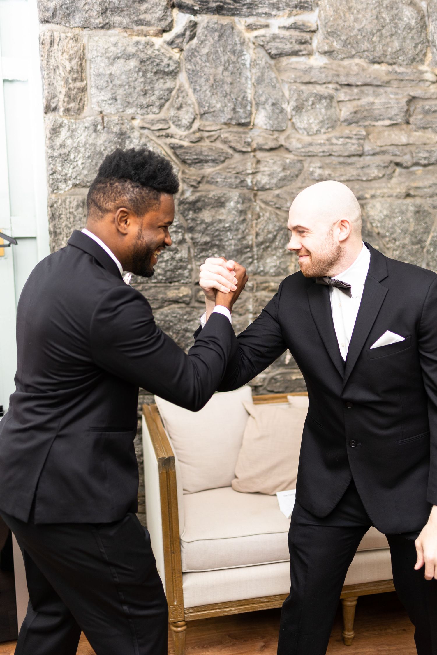 Two people in formal wear share a playful moment during wedding preparations.