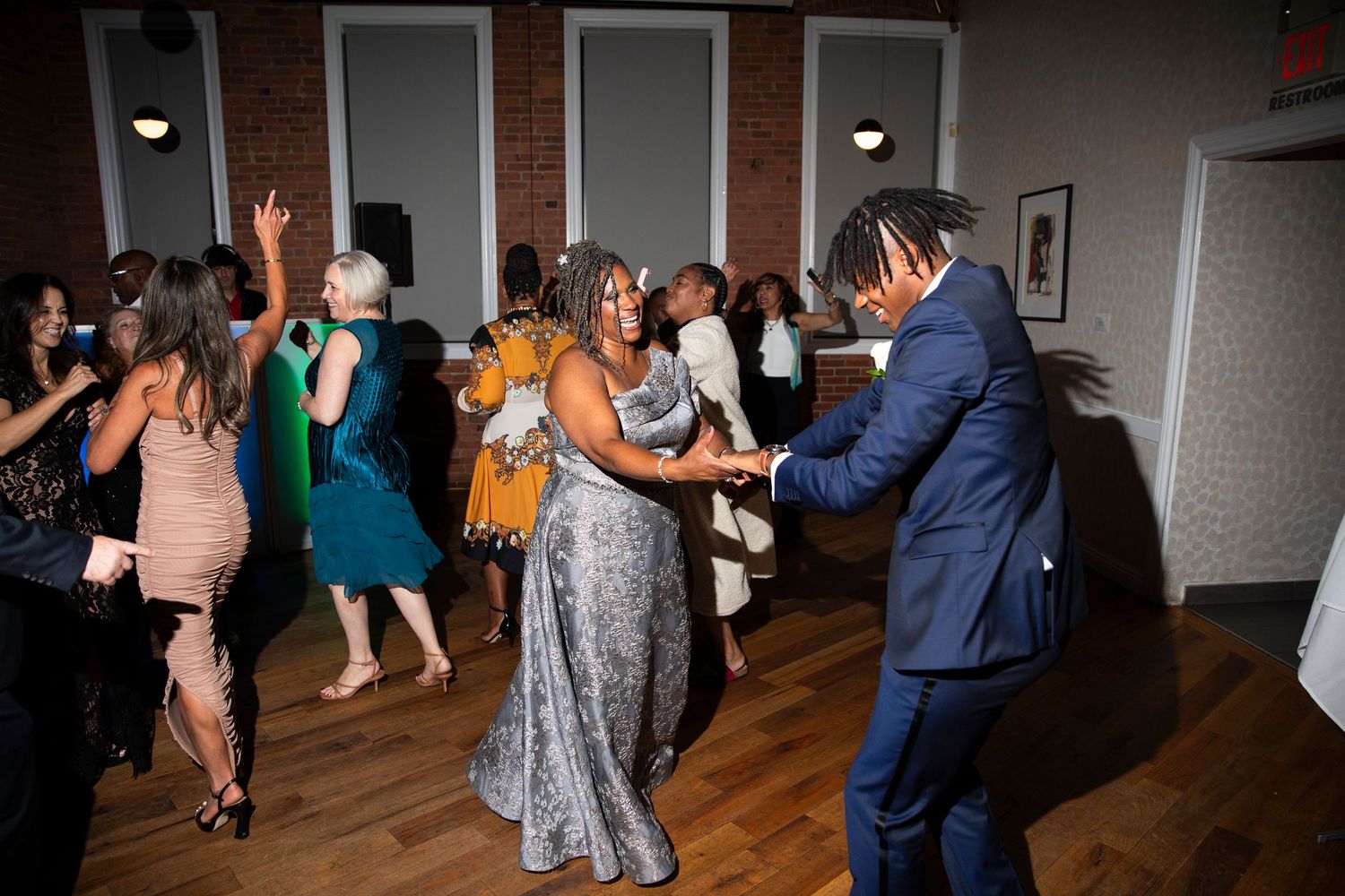 Wedding reception guests dancing and celebrating on a wooden dance floor.