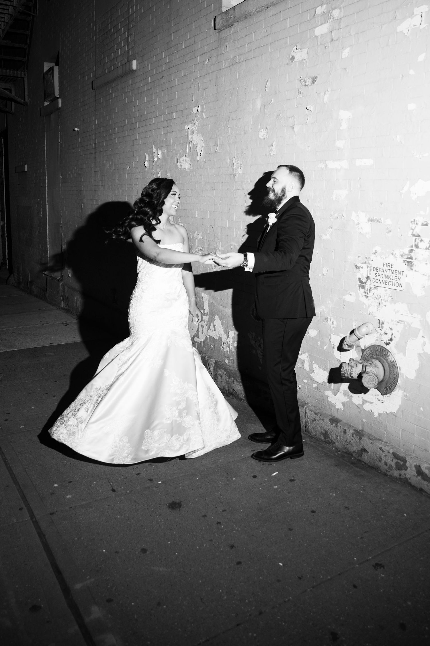 Black and white sequence of a bride and groom dancing in an artistic pose against a textured wall.