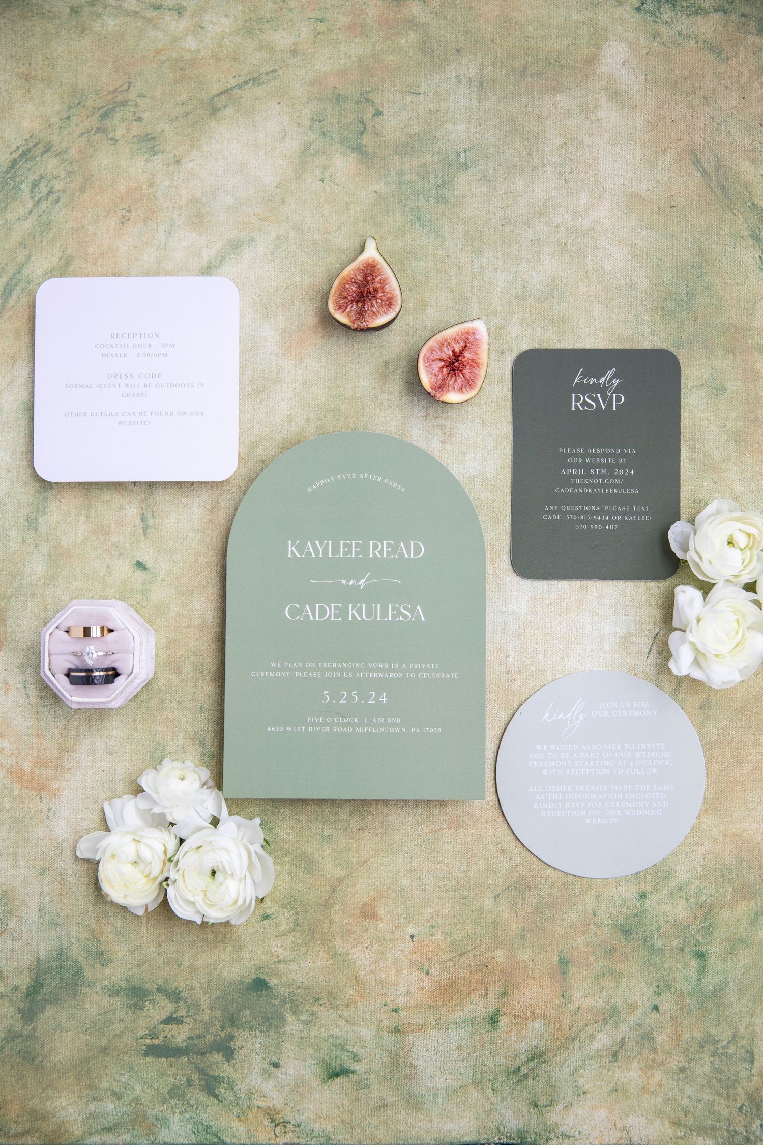 Elegant sage green and white wedding invitation suite with figs and floral accents on textured background.