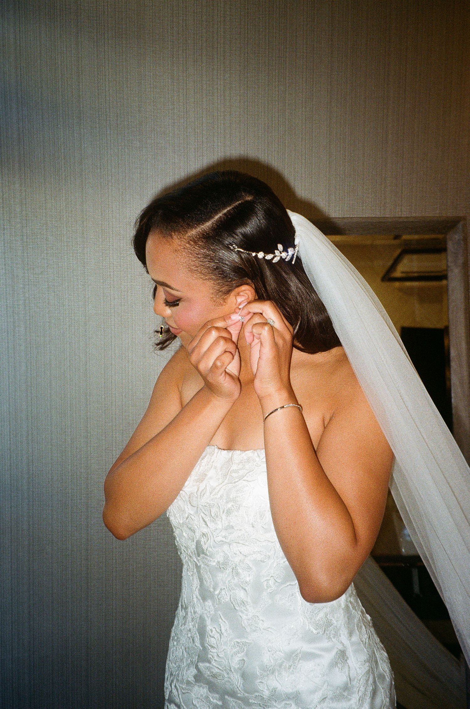 Close-up of bridal jewelry and veil details during wedding preparations.