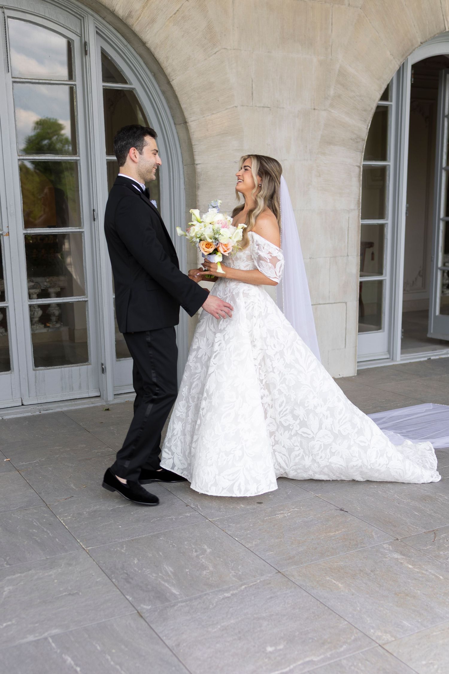 Wedding couple sharing intimate first look moment on an elegant stone veranda.