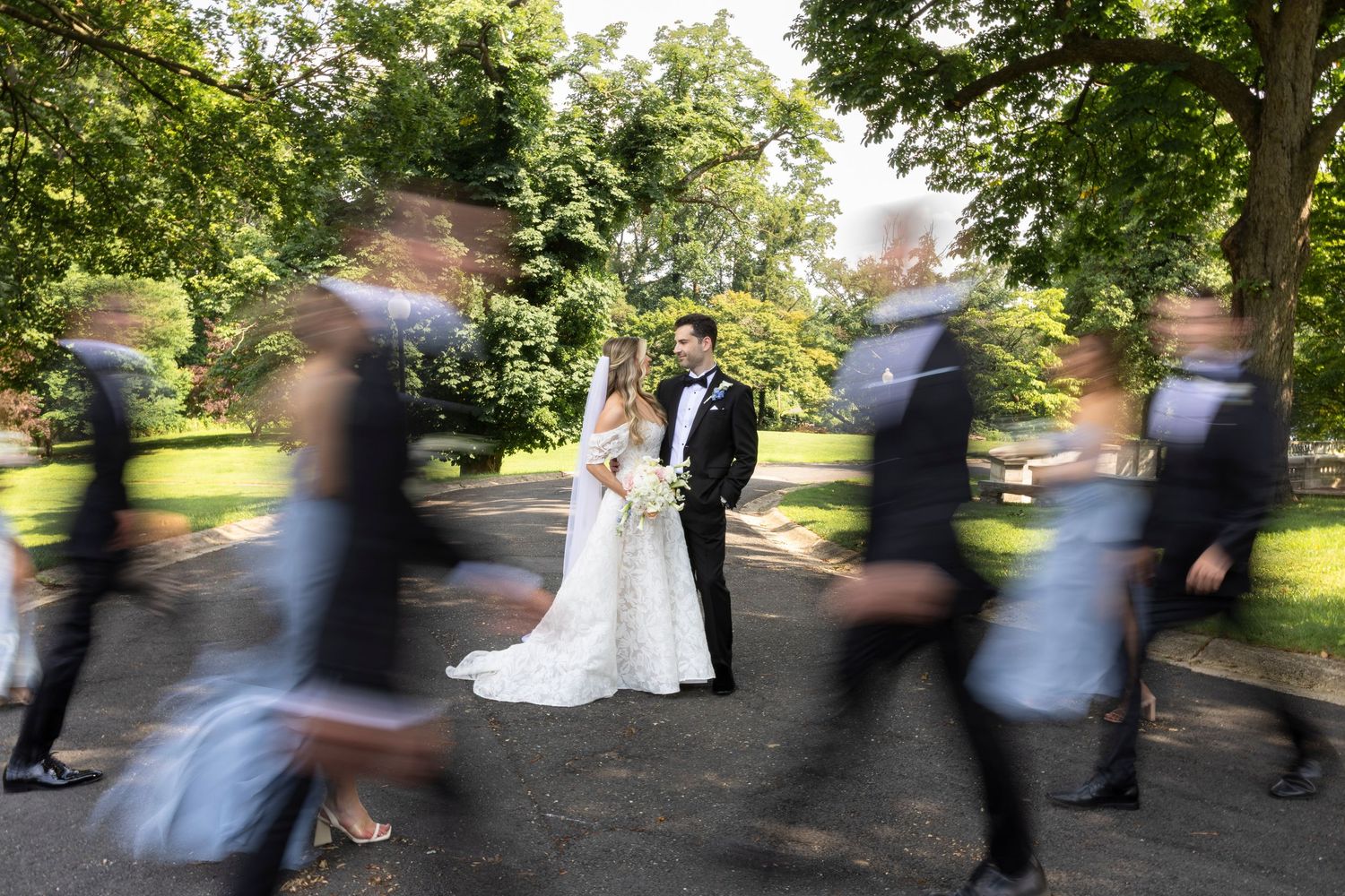 Motion blur photo of wedding party walking on outdoor path.