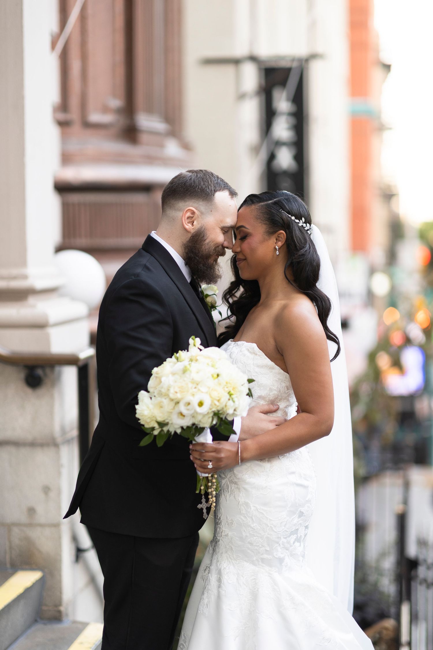 Intimate wedding moment captured on urban building steps with white bouquet.