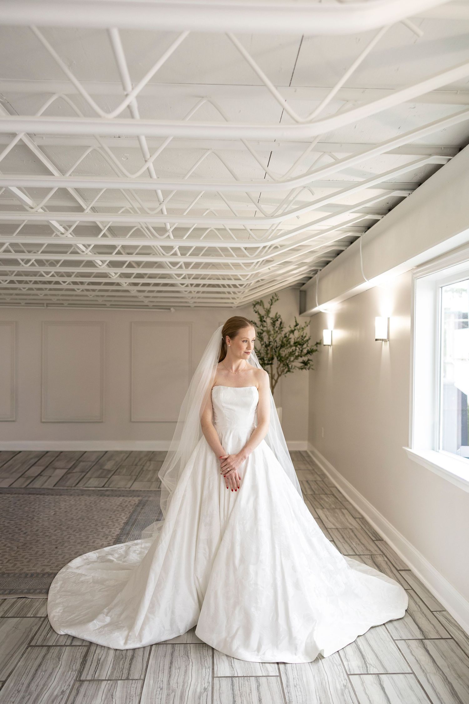 Classic ballgown wedding dress showcased in bright studio with exposed ceiling and wooden floors.