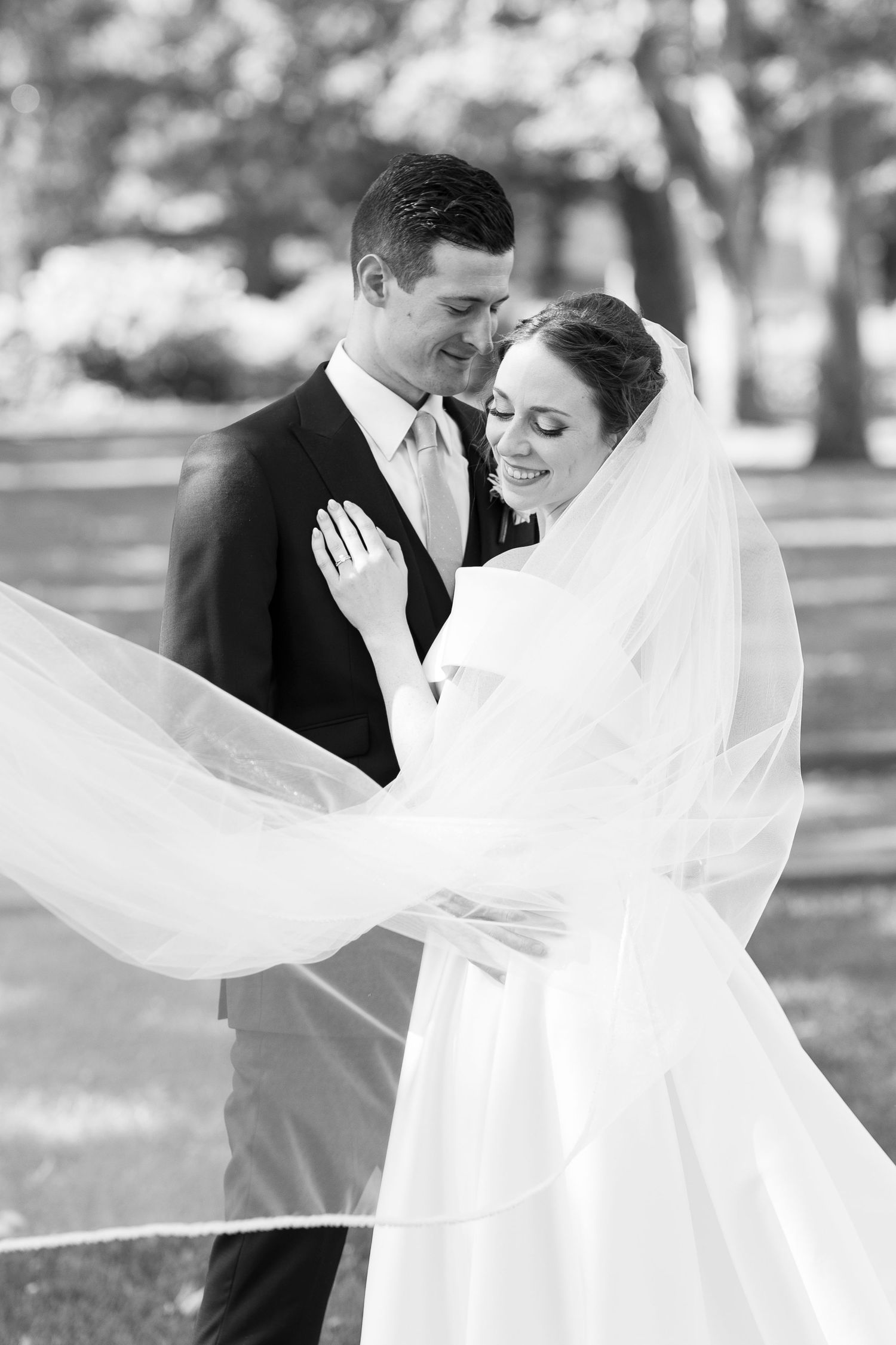 Black and white photos of bride and groom with flowing veil in natural outdoor setting.