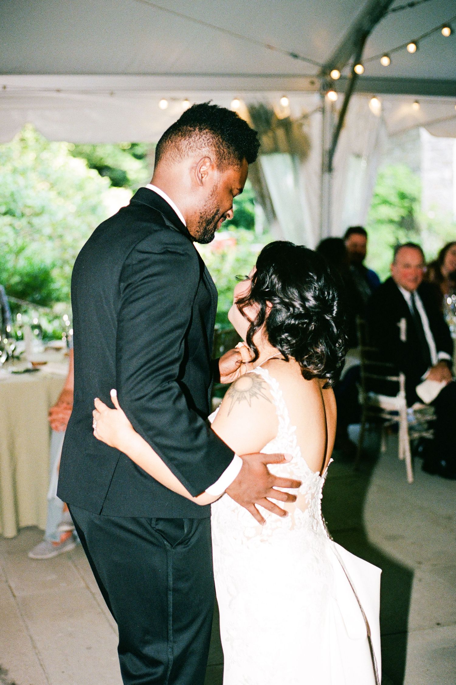 Romantic wedding dance sequence showing couple in black suit and white dress embracing under twinkling lights.