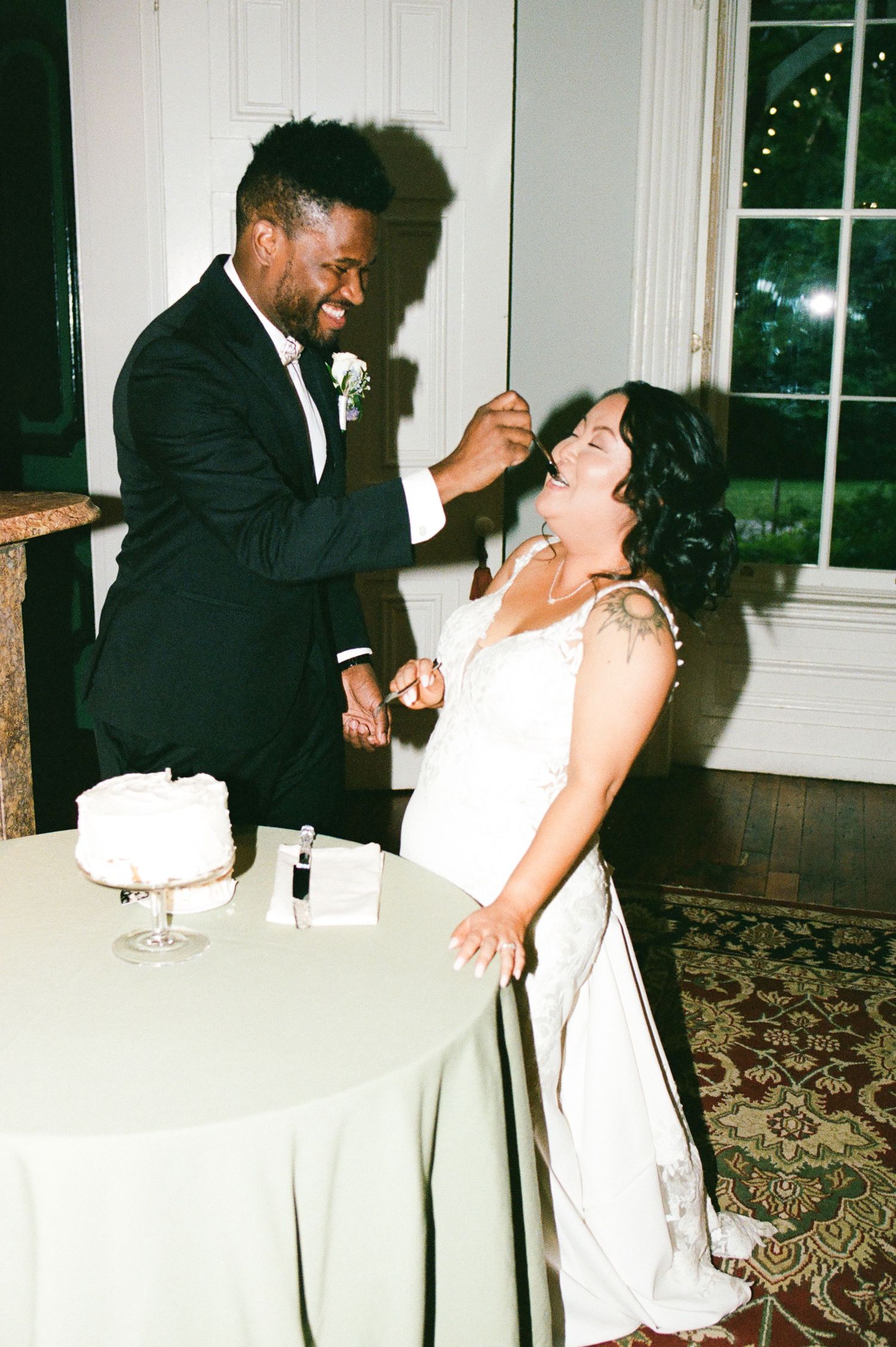 Candid reception moments of couple laughing and dancing by table with wine glasses.