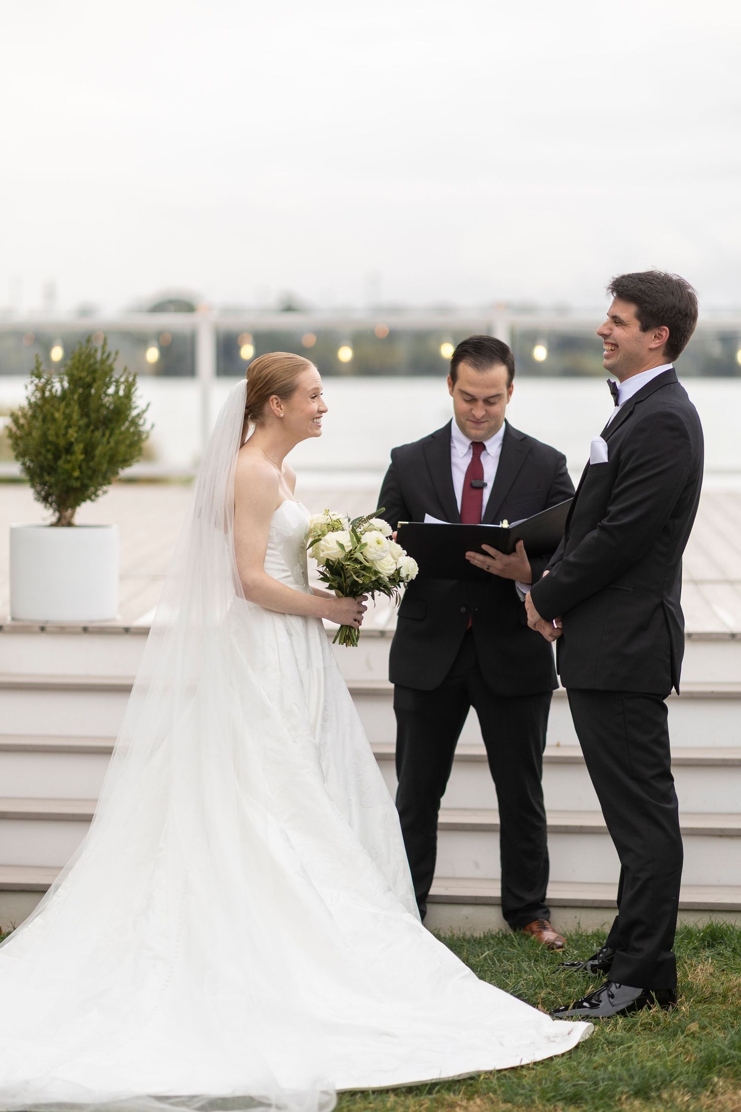 A wedding ceremony in progress on waterfront steps with the couple and officiant.