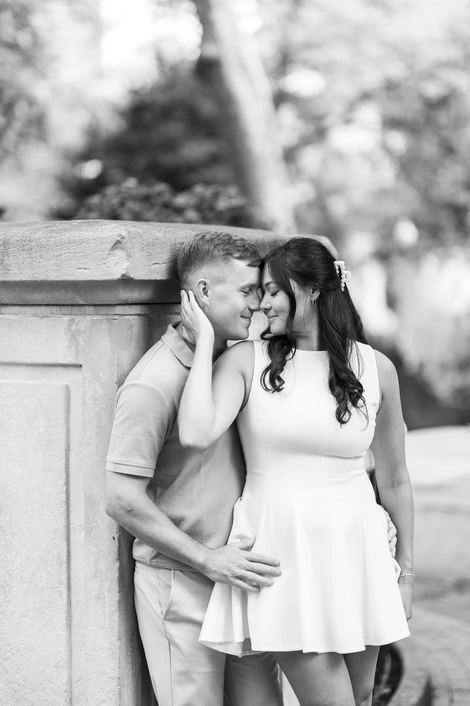 Black and white photo of a couple sharing an intimate moment in a park.