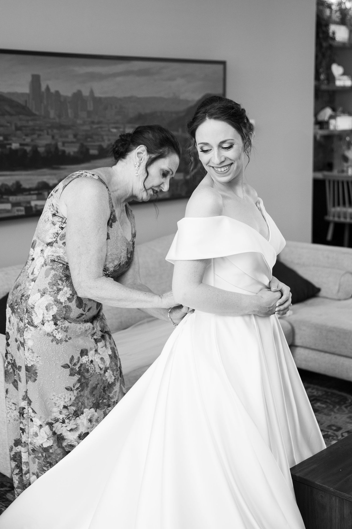 Black and white photo showing details of a wedding dress being adjusted.