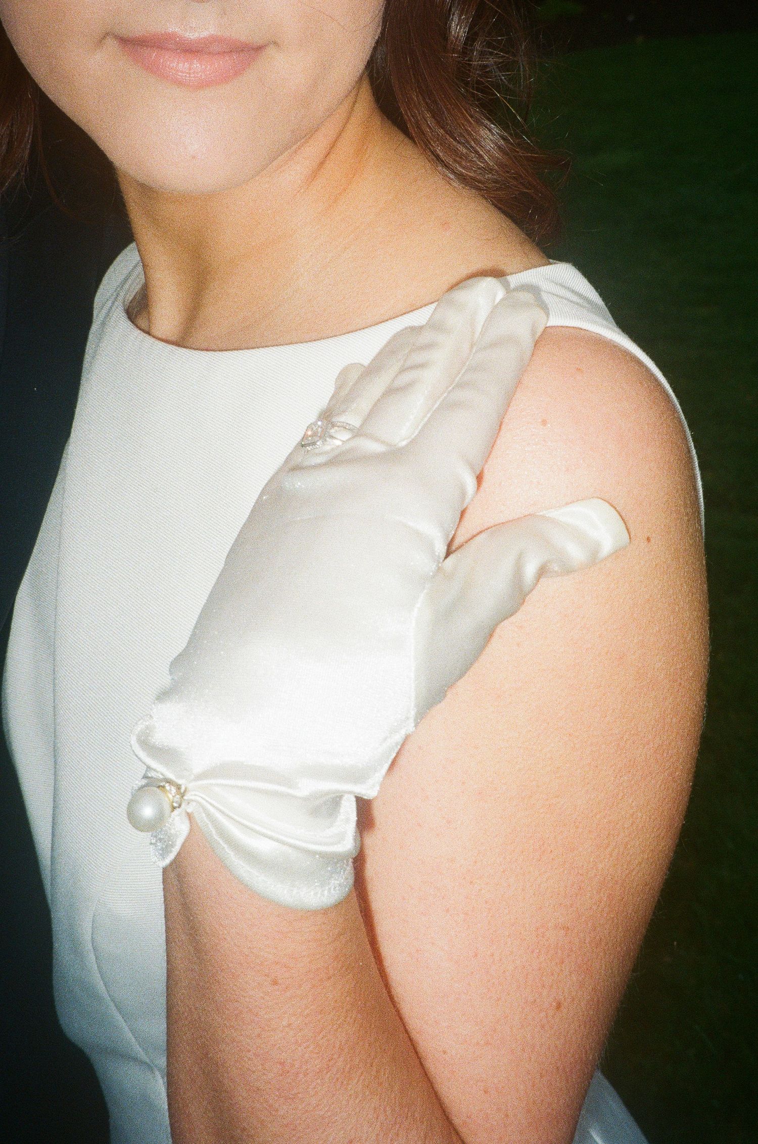 Close-up detail of a white satin wedding dress sleeve and bodice.