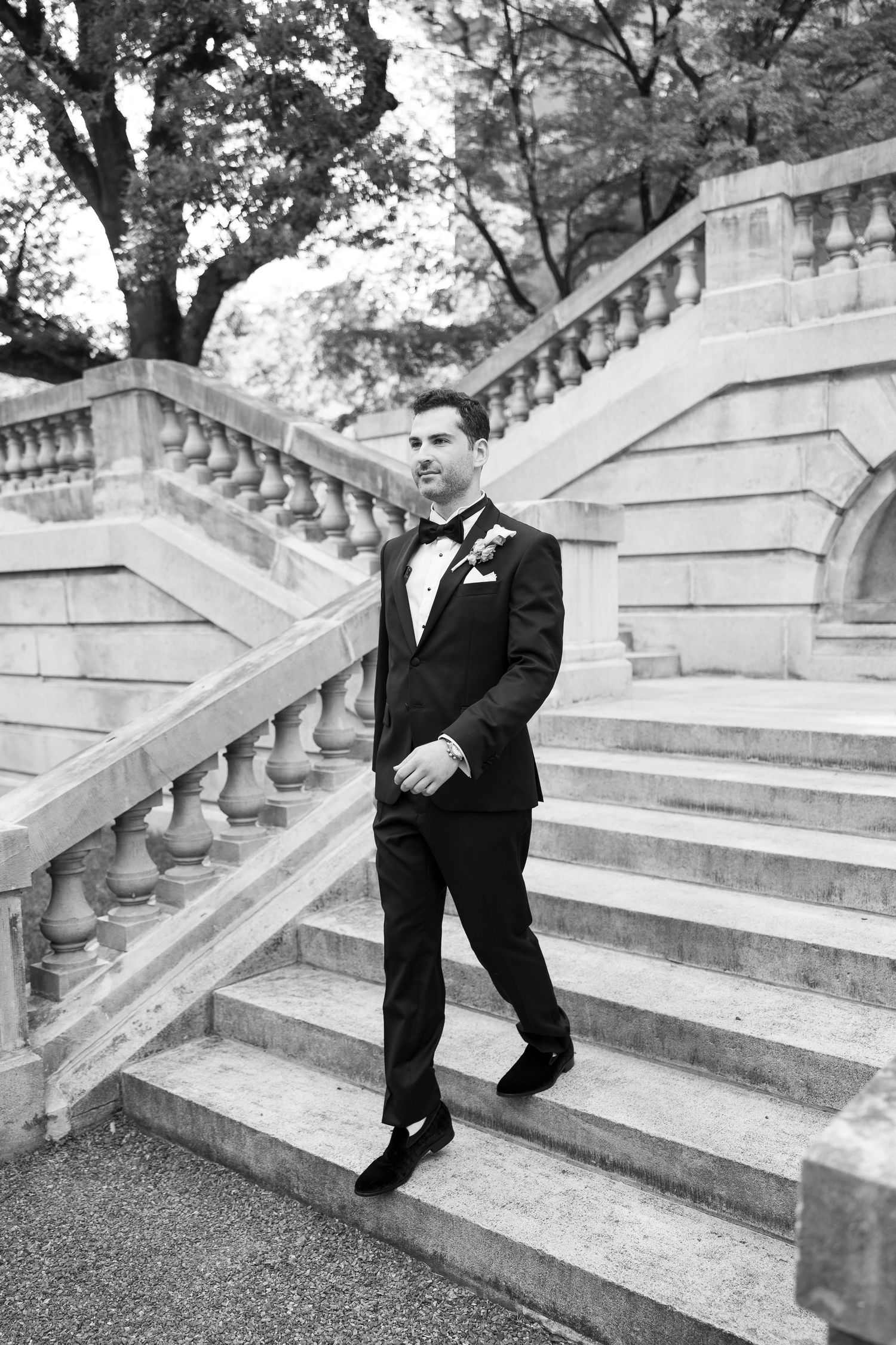 Black and white photo of person in formal wear ascending stone steps.