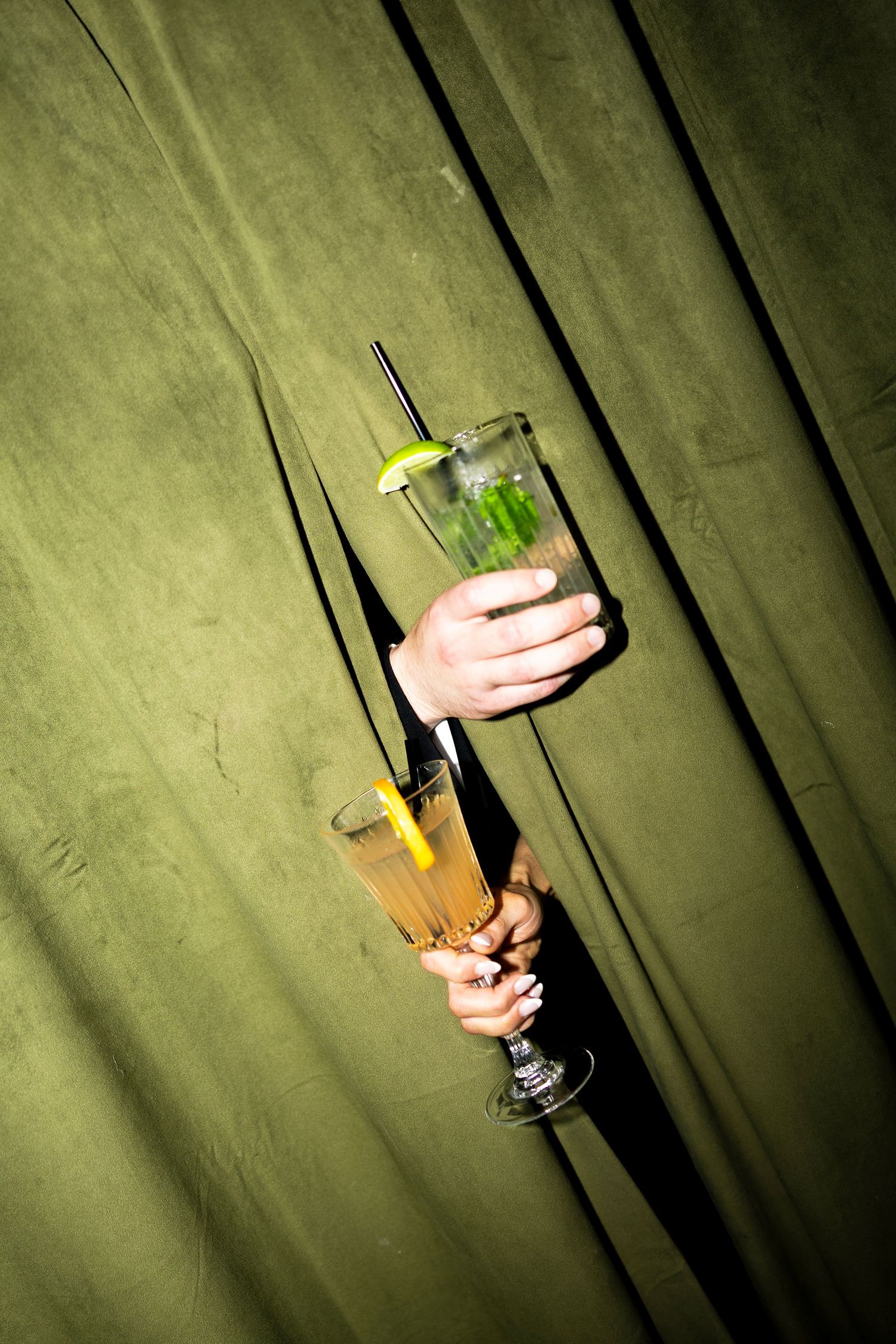 Colorful cocktails with garnishes displayed against a green backdrop.