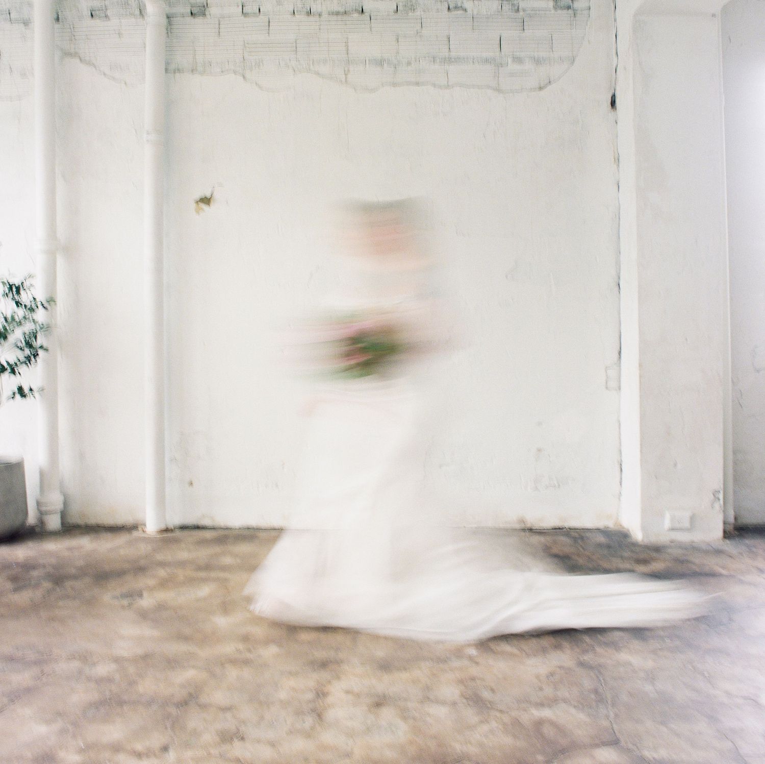 Minimalist white industrial space with concrete floors and exposed walls.