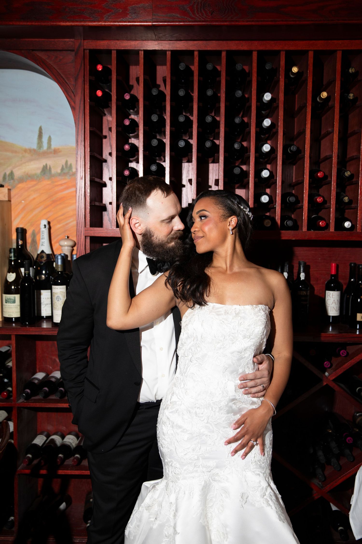 Romantic moment between newlyweds in front of a wine rack display.
