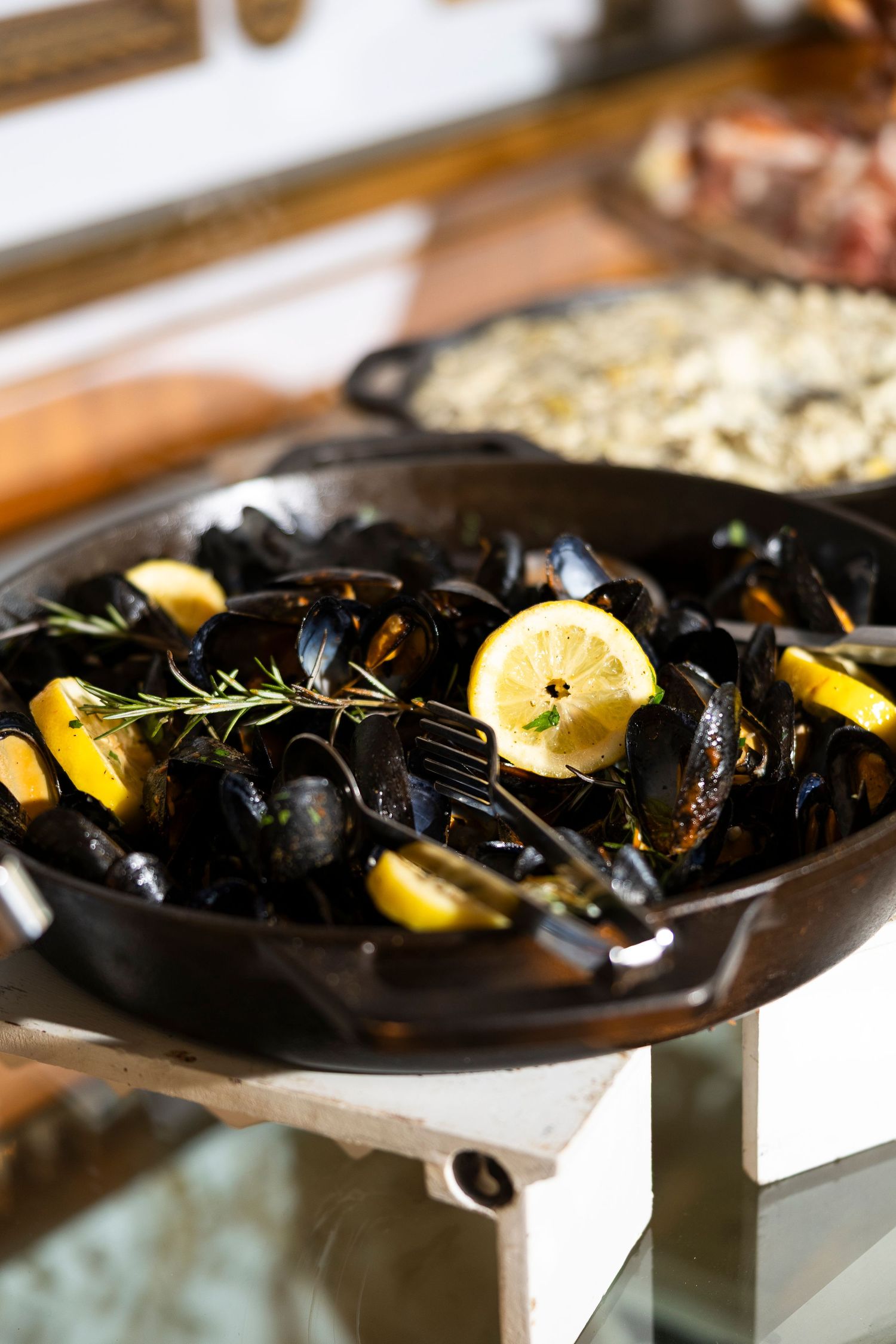 Fresh mussels served on a dark platter with lemon and herbs.