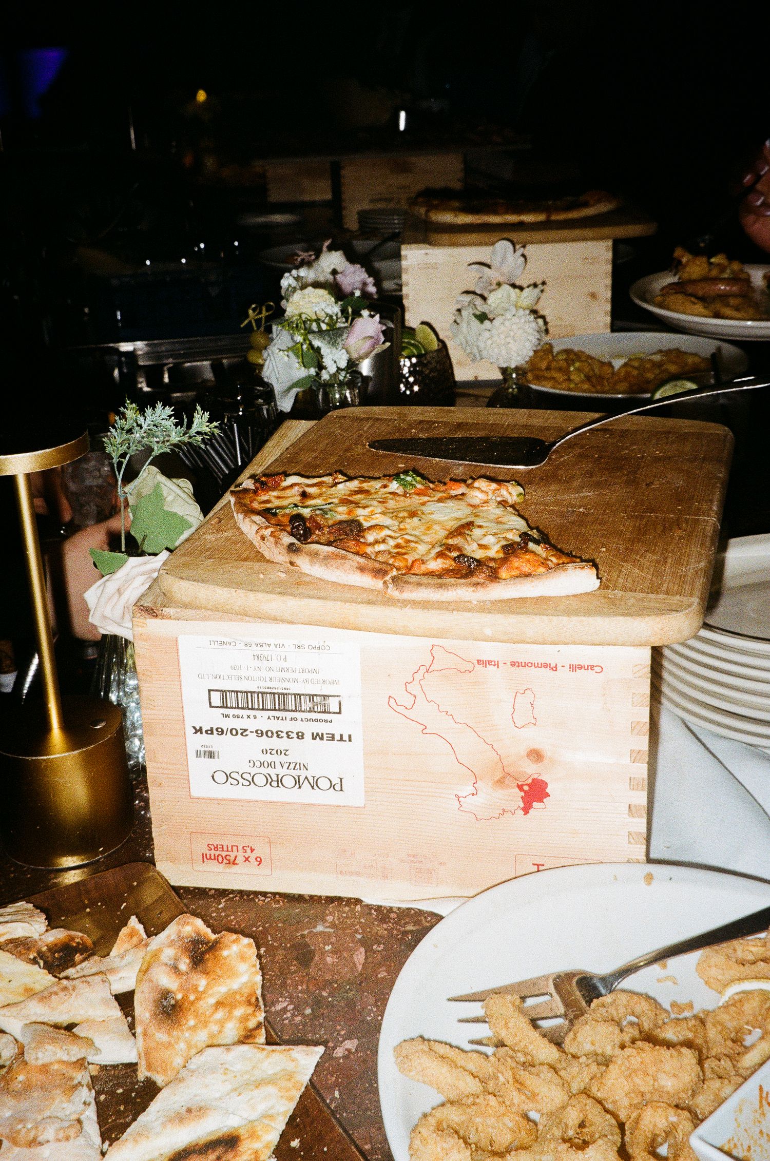 Wooden boxes and food platters displayed on a rustic table at a wedding reception.