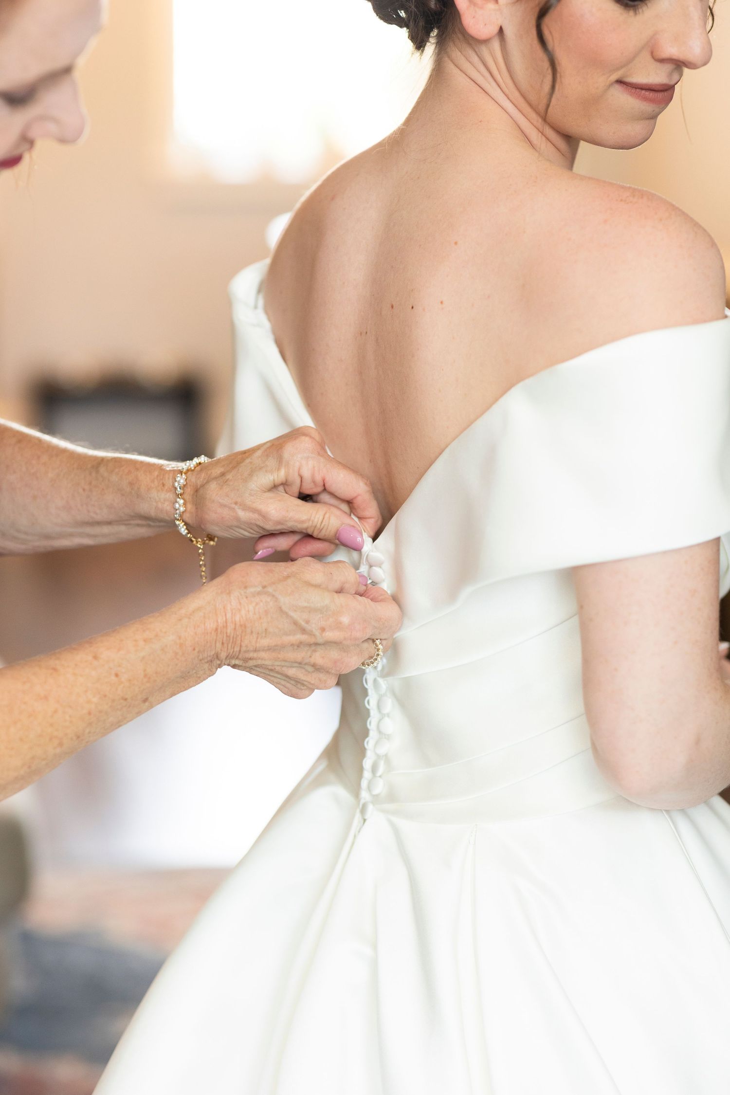 Close-up details of a white wedding dress being fastened.