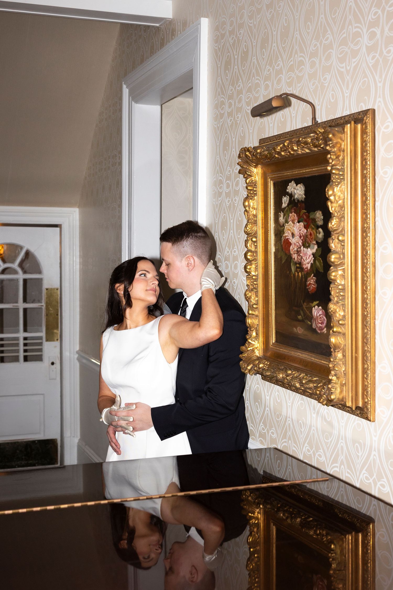 A romantic moment shared between a couple by a grand piano with a gilded frame on the wall.