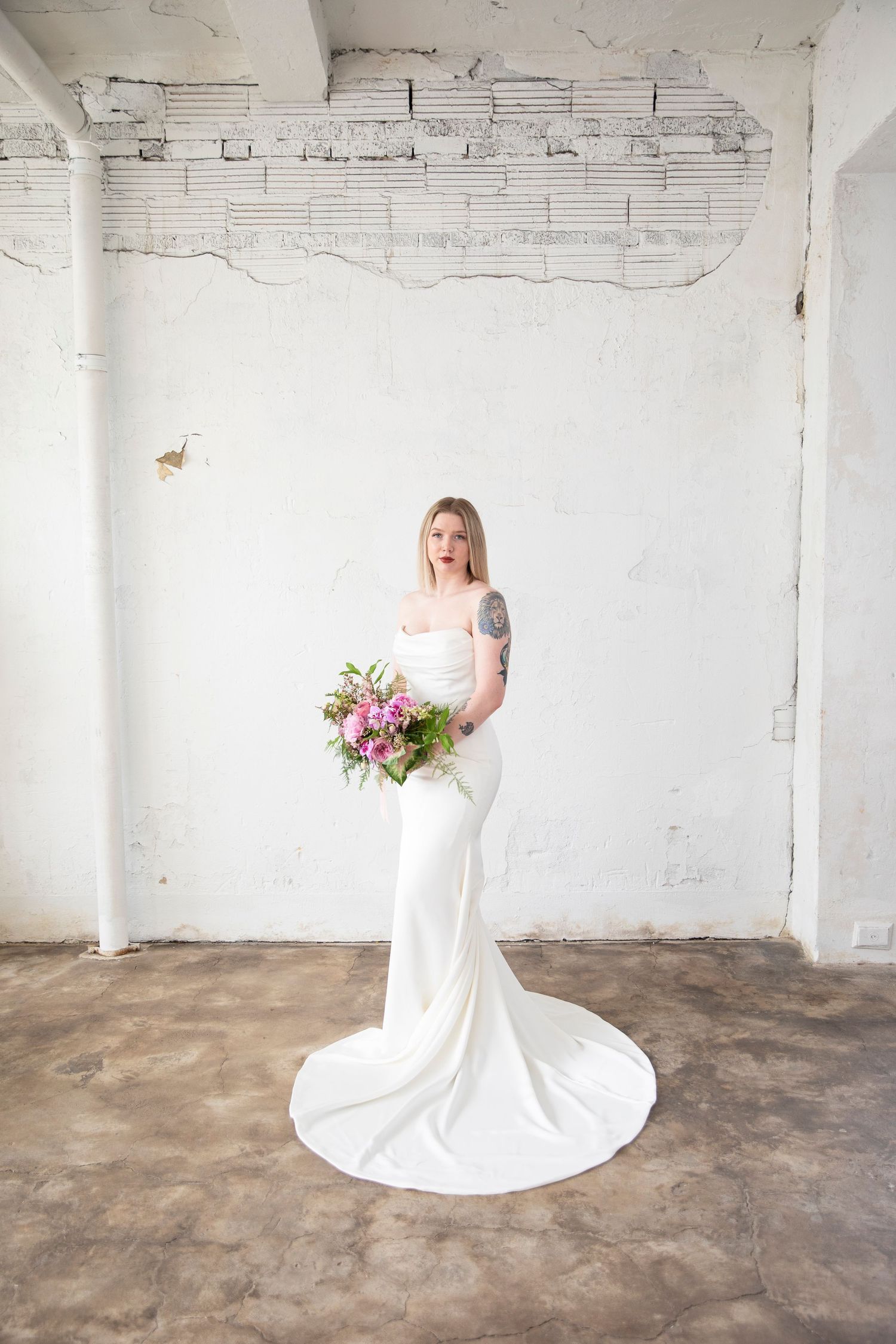 Elegant bridal portraits in white gown against industrial white brick space.