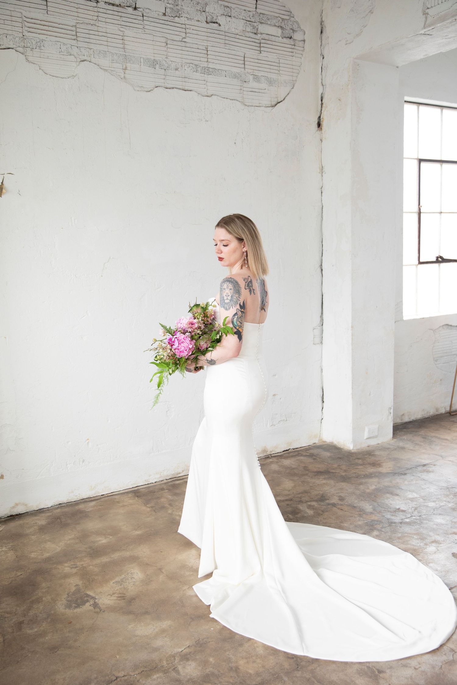 Bridal portrait in flowing white gown in industrial space.
