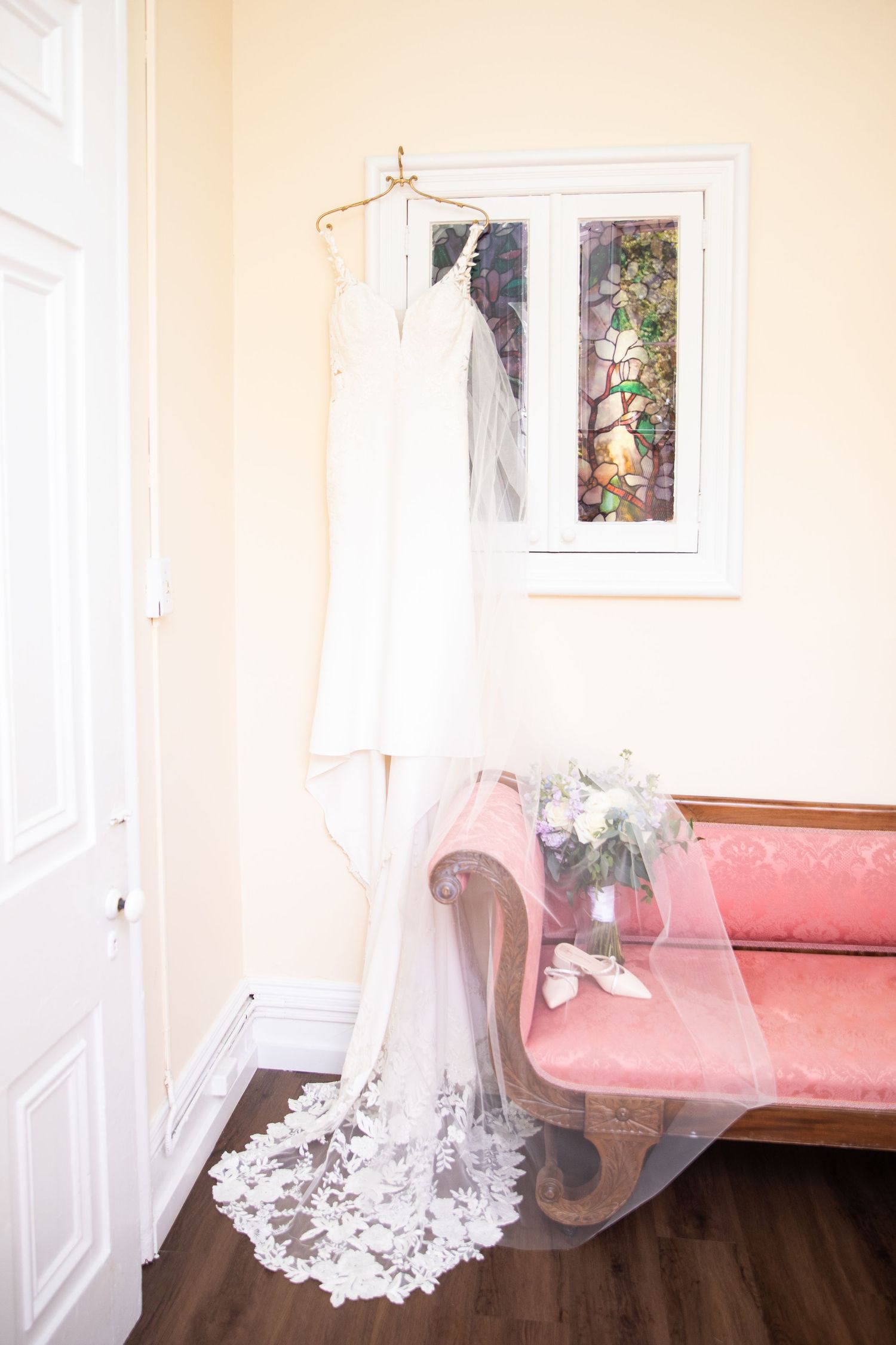 A delicate lace wedding veil draped elegantly across a pink couch in a bright room.