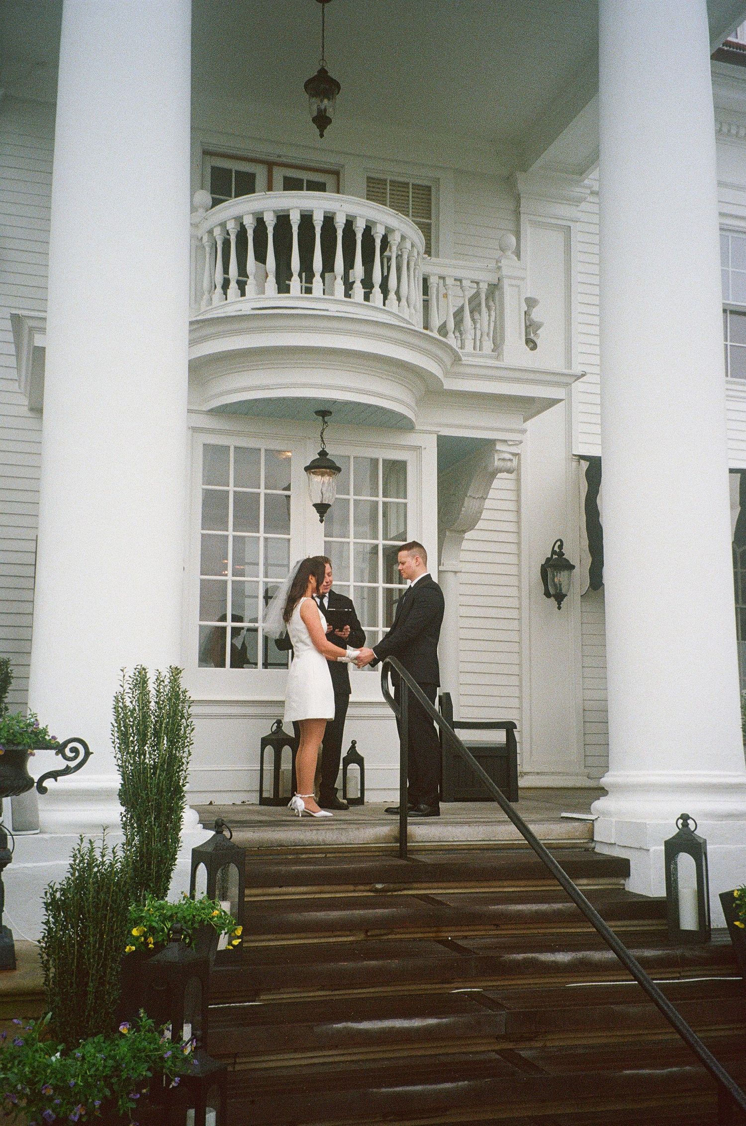 A wedding ceremony taking place on the steps of a grand white columned building.