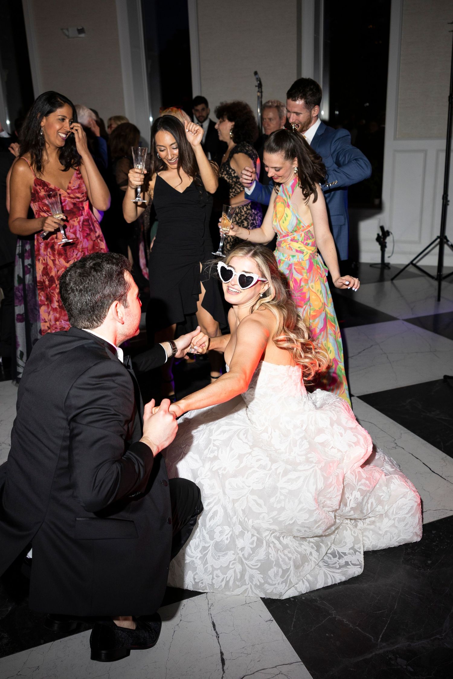 Wedding guests dancing and celebrating on a black and white checkered dance floor.