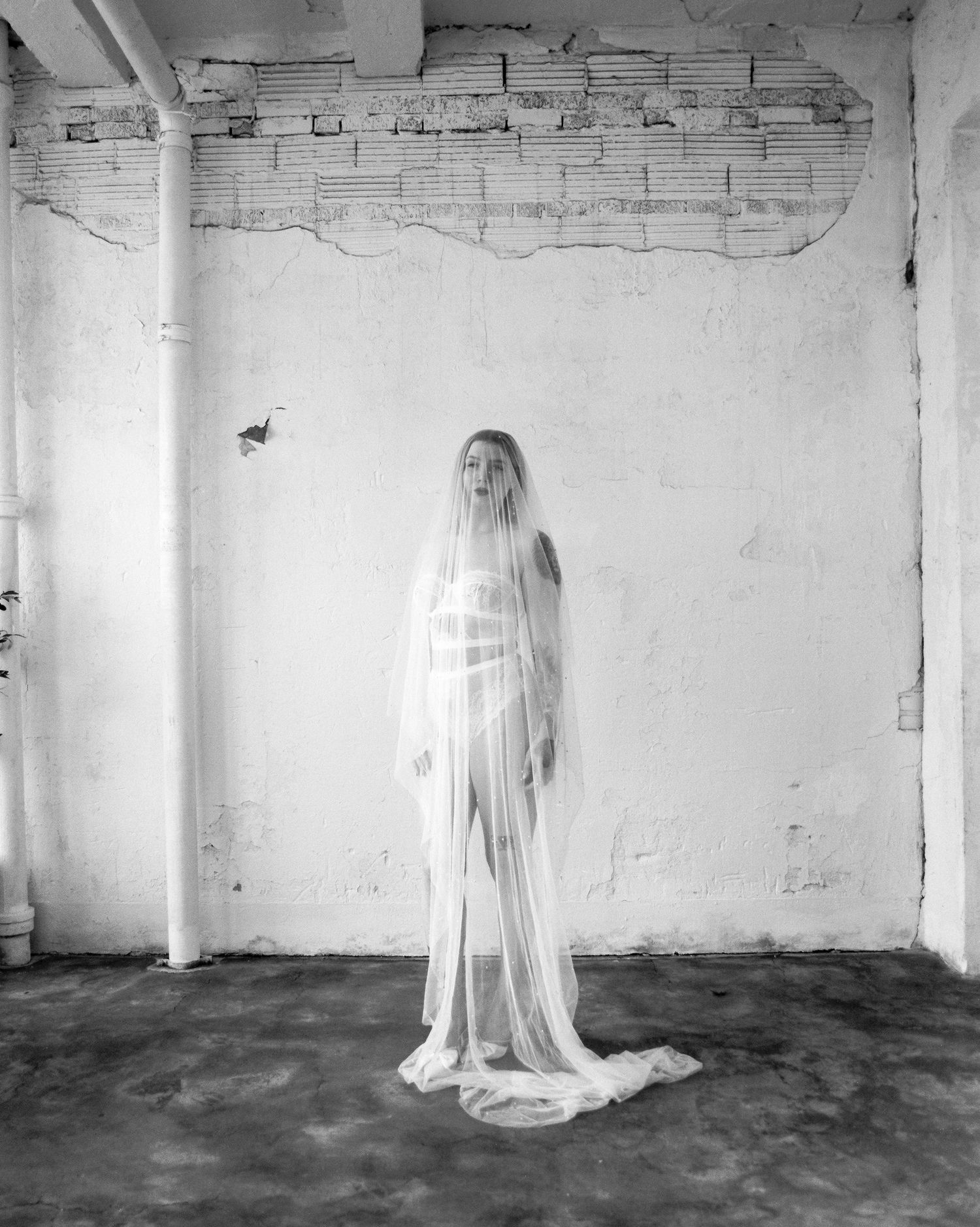 Black and white bridal portraits in minimalist industrial space with dramatic veil movement.