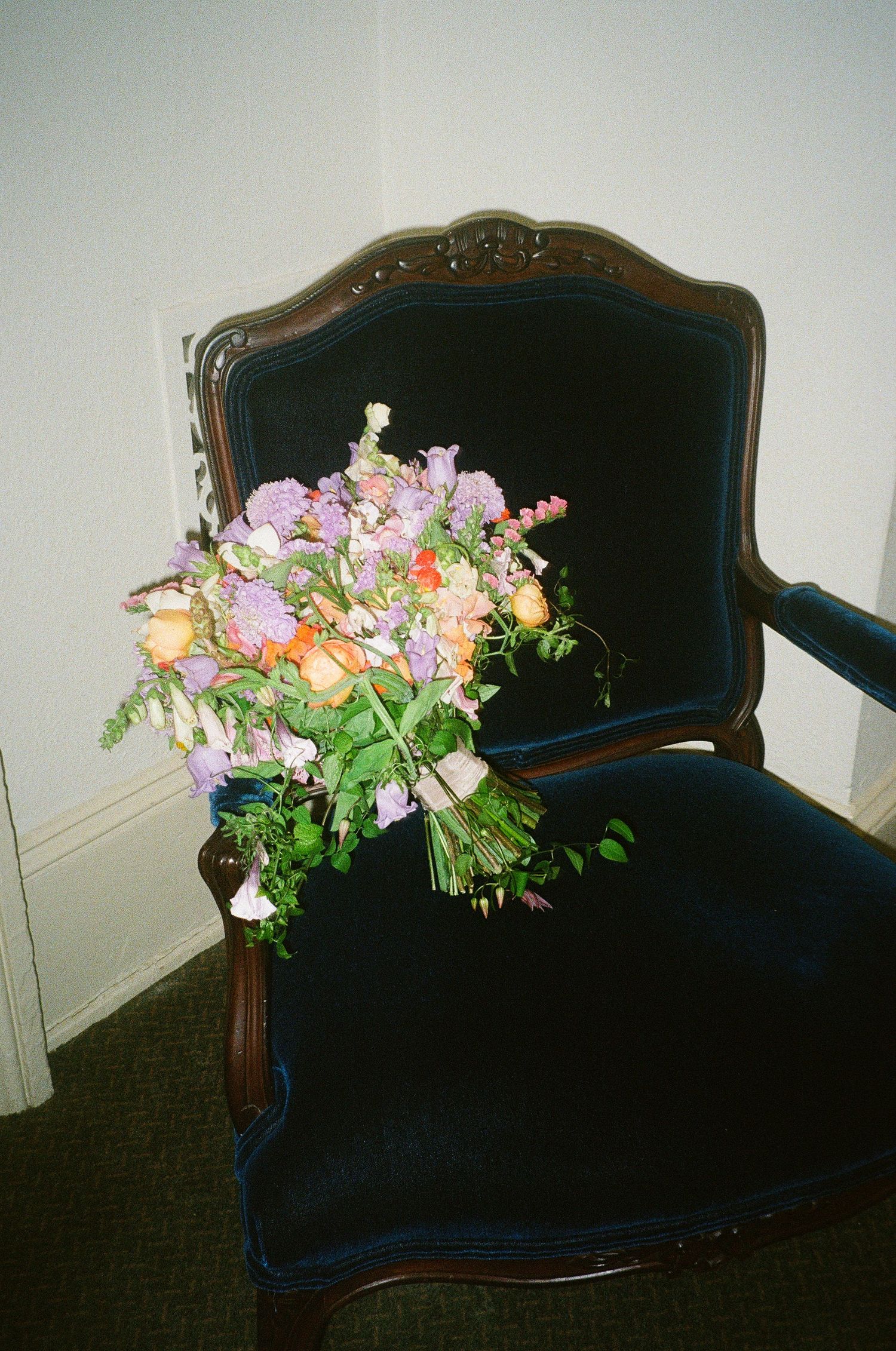 Antique navy blue velvet settee decorated with pastel floral arrangements.