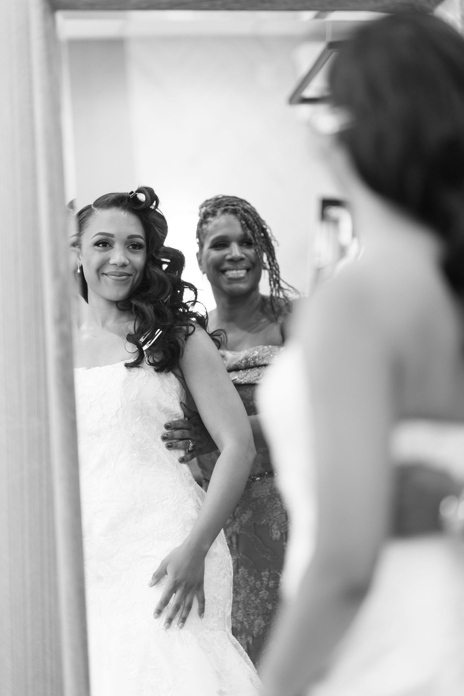 Joyful moments captured during wedding dress preparations in a bright room.