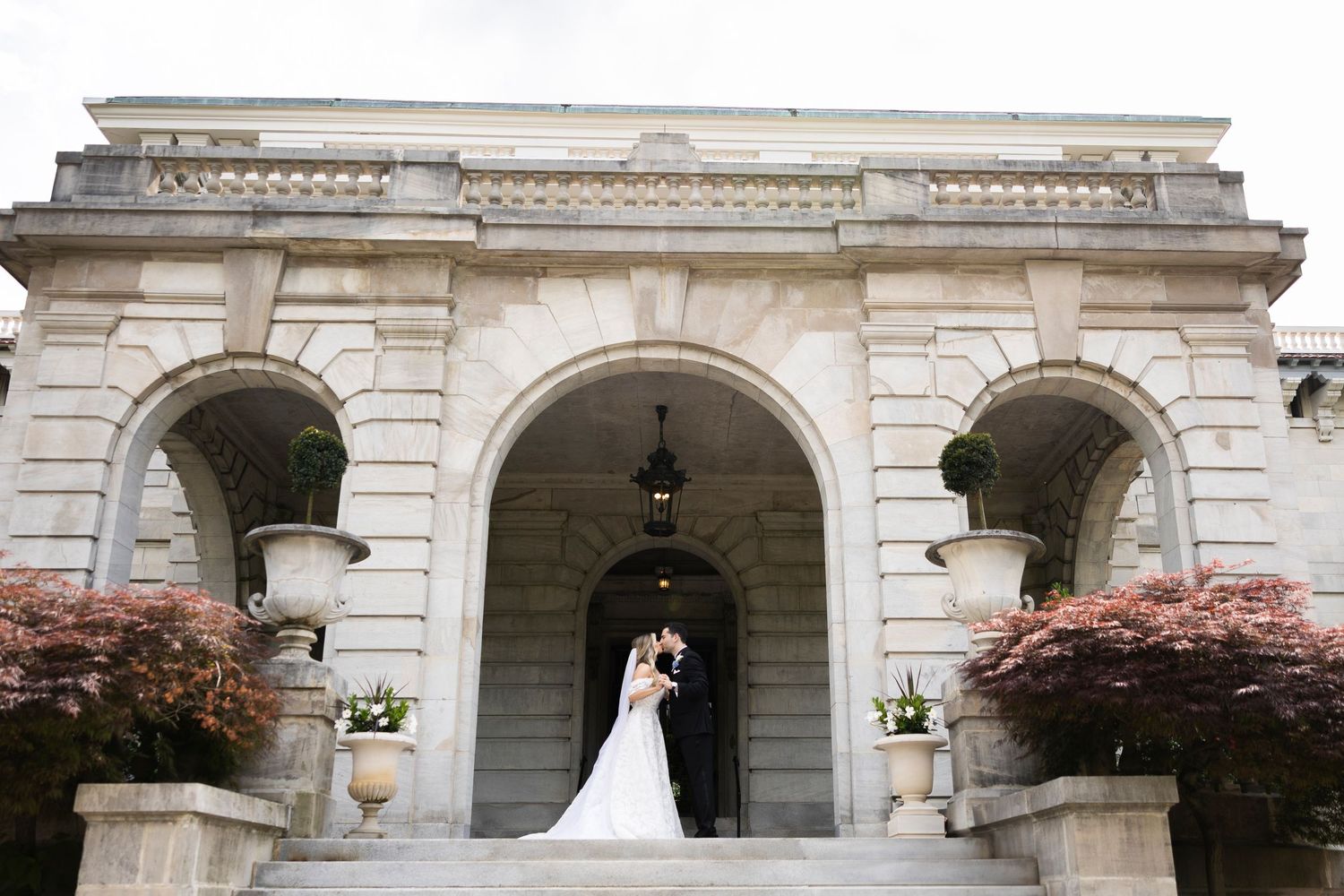 Wide architectural shot of historic building facade with wedding couple in the distance.