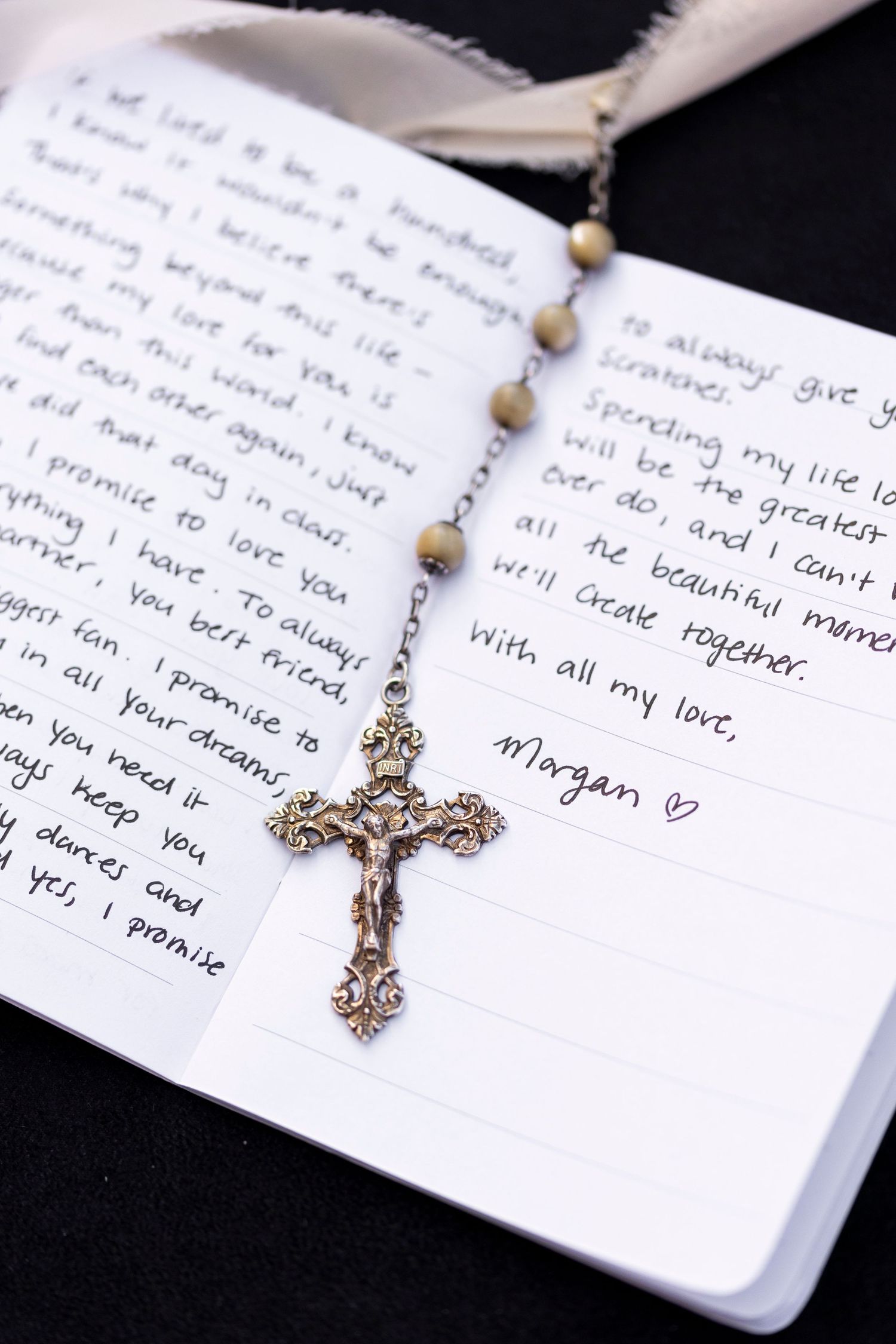 Handwritten wedding vows displayed with delicate gold necklace on white paper.