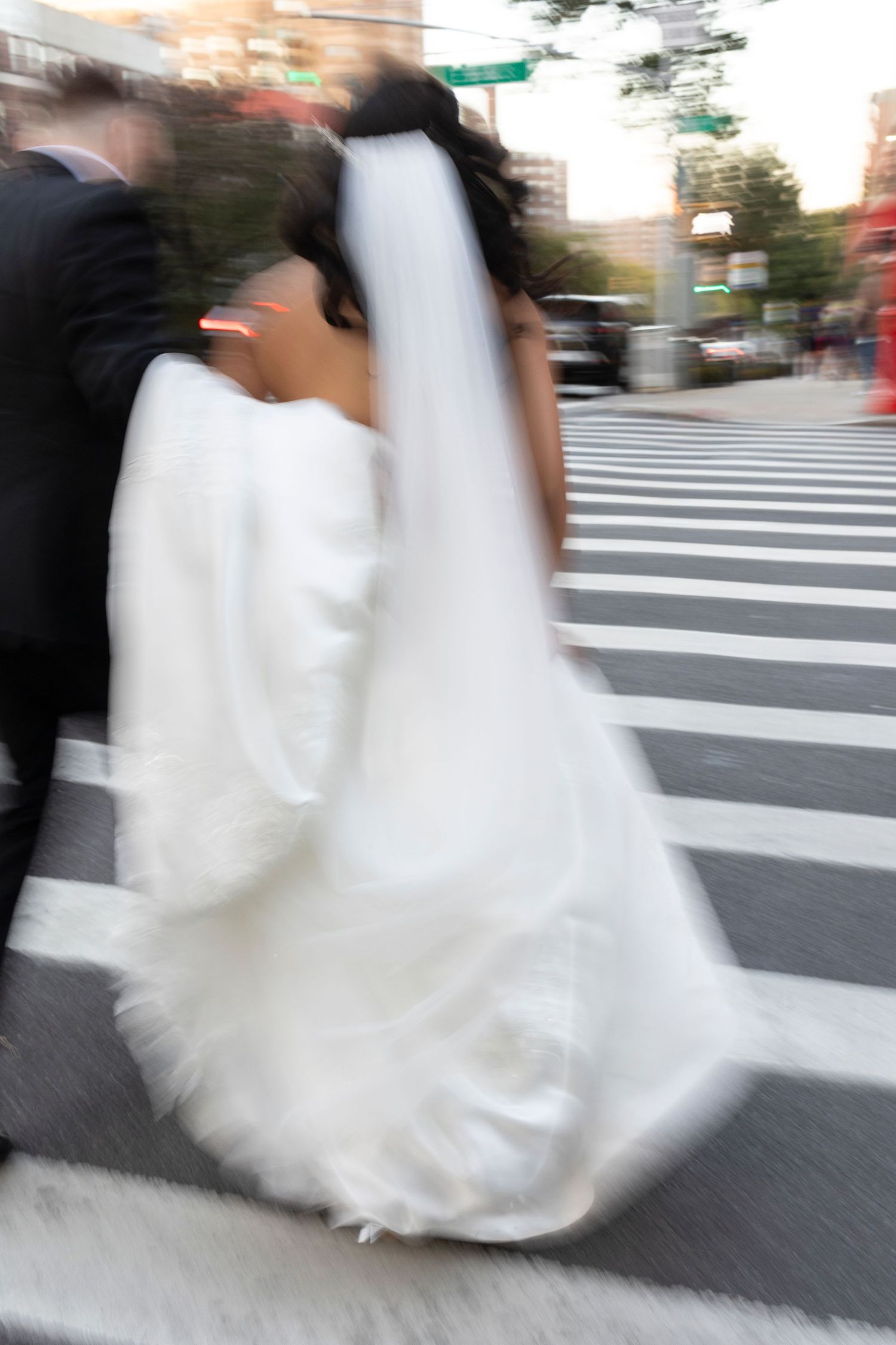 Dynamic shot of a flowing white wedding gown in motion on a crosswalk.