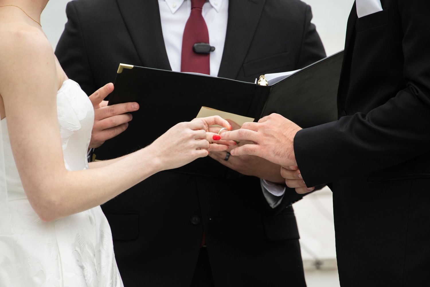 Close-up of wedding ceremony participants exchanging vows on a sunny day.